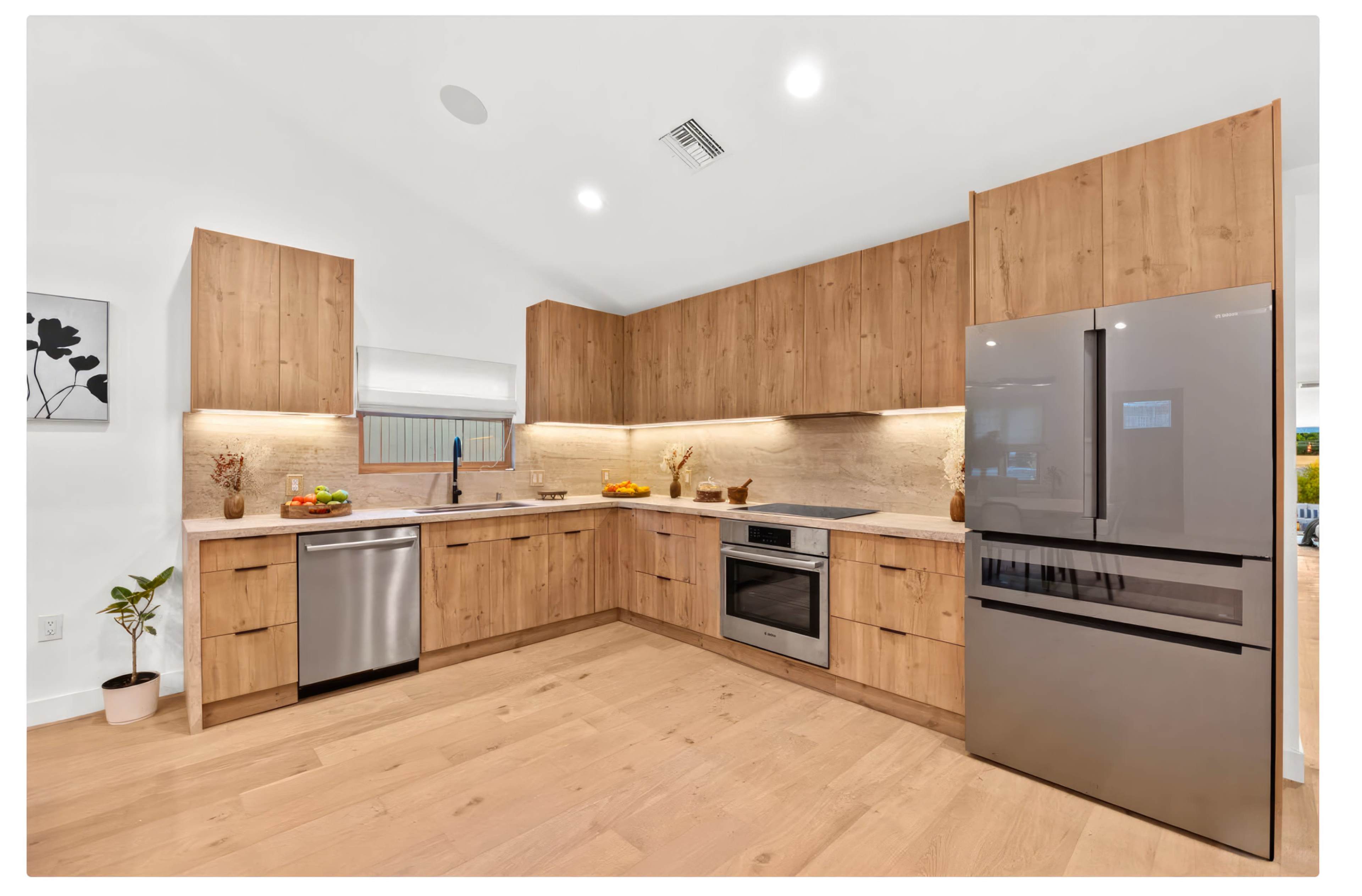 The kitchen features wooden cabinetry and modern stainless steel appliances, with a clean layout and bright lighting.