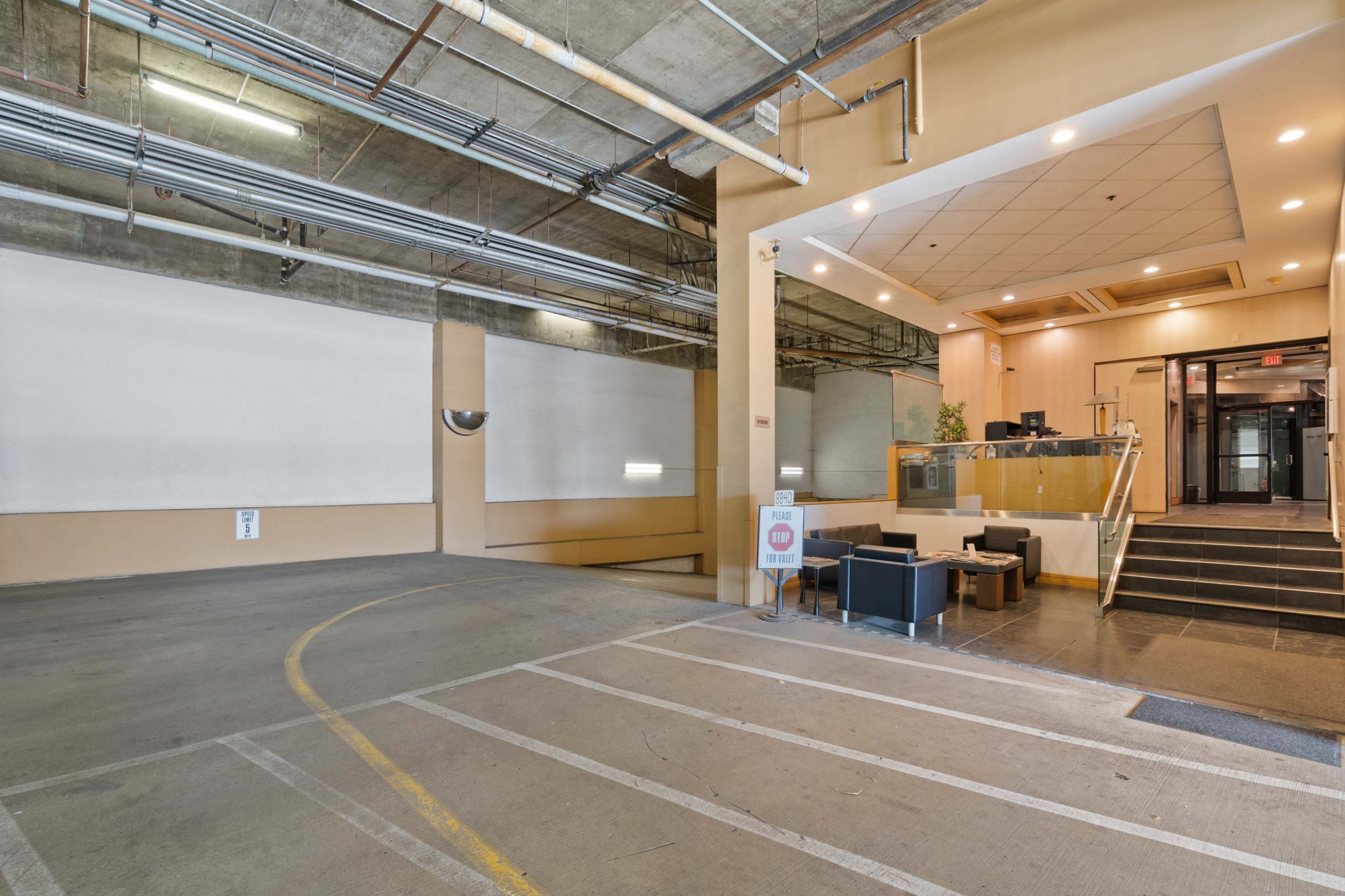 The image shows an empty lobby area of a building with a reception desk and seating arranged on the left side.