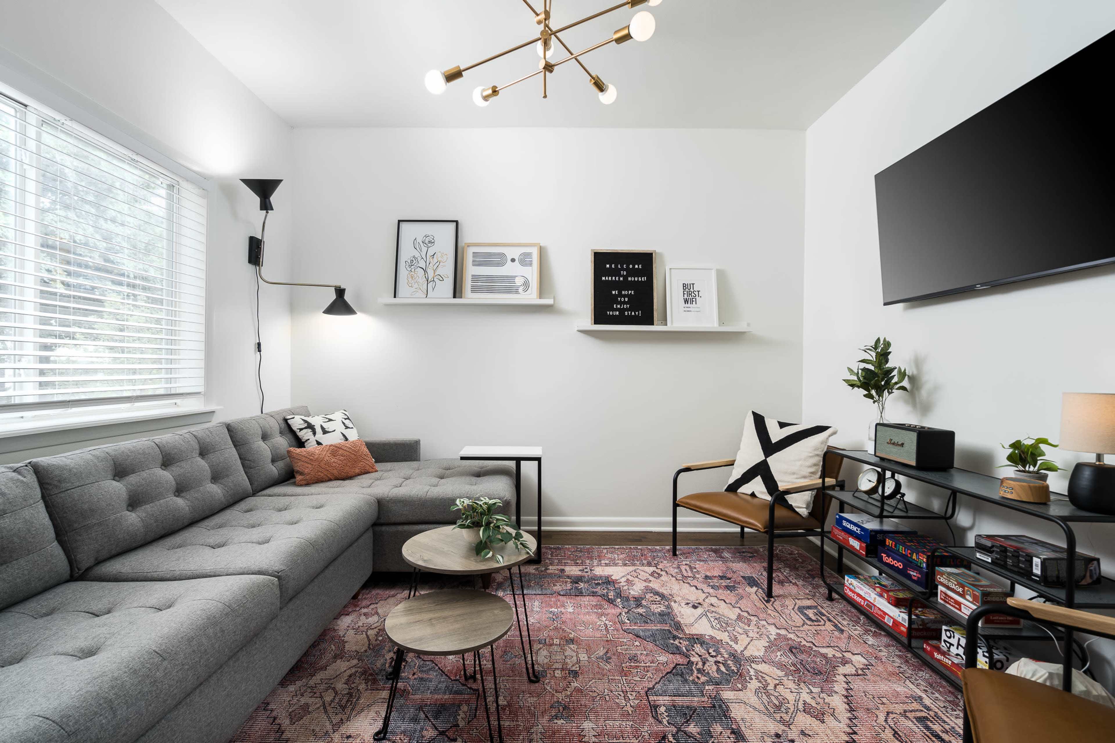 A modern living room features a gray sofa, a two-tiered coffee table, decorative wall art, and a television mounted on a white wall.