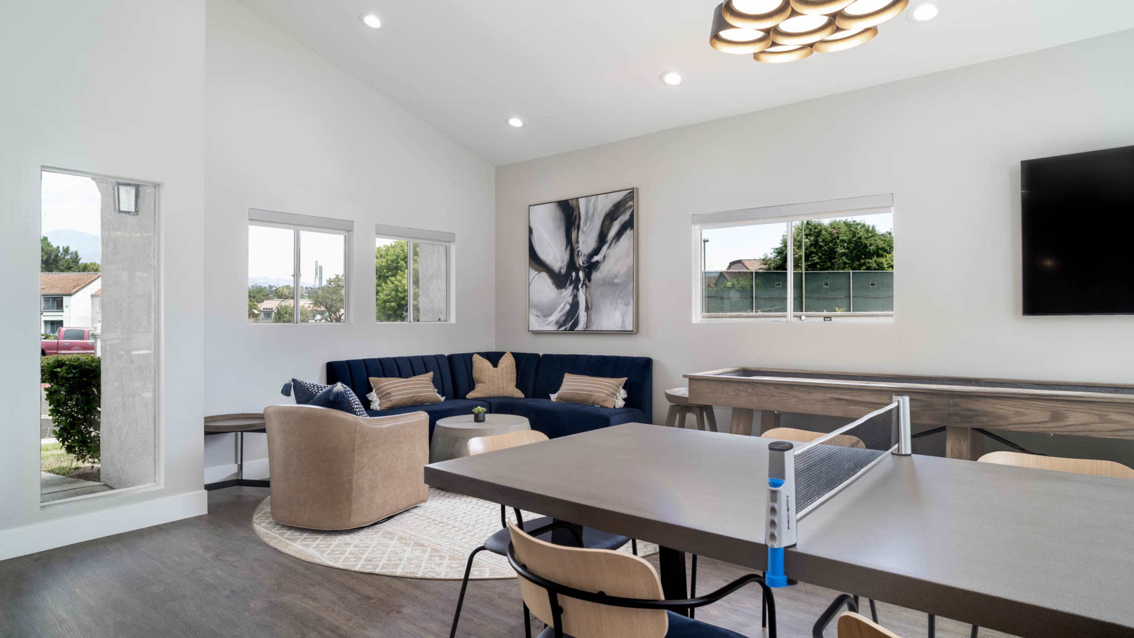 A modern living space with a sectional sofa, a dining table, and large windows allowing natural light to fill the room.