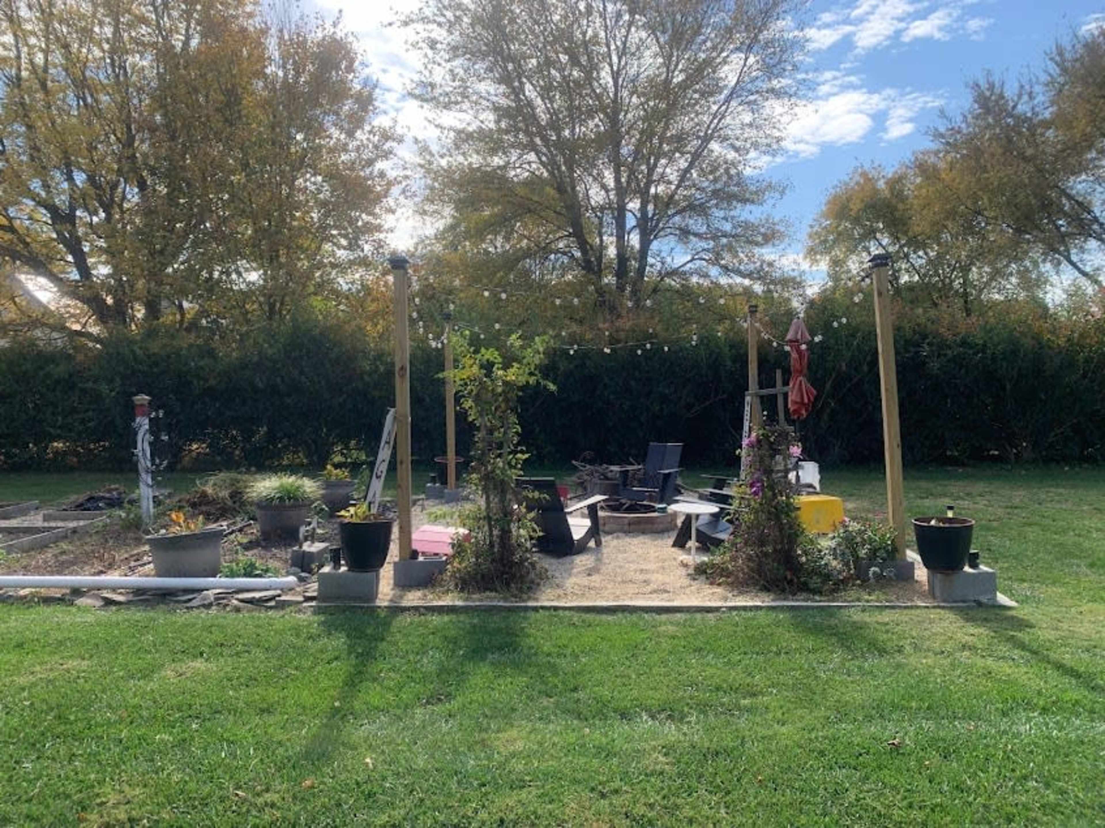 A landscaped backyard with seating areas, plants, and a gravel surface surrounded by trees and bushes.