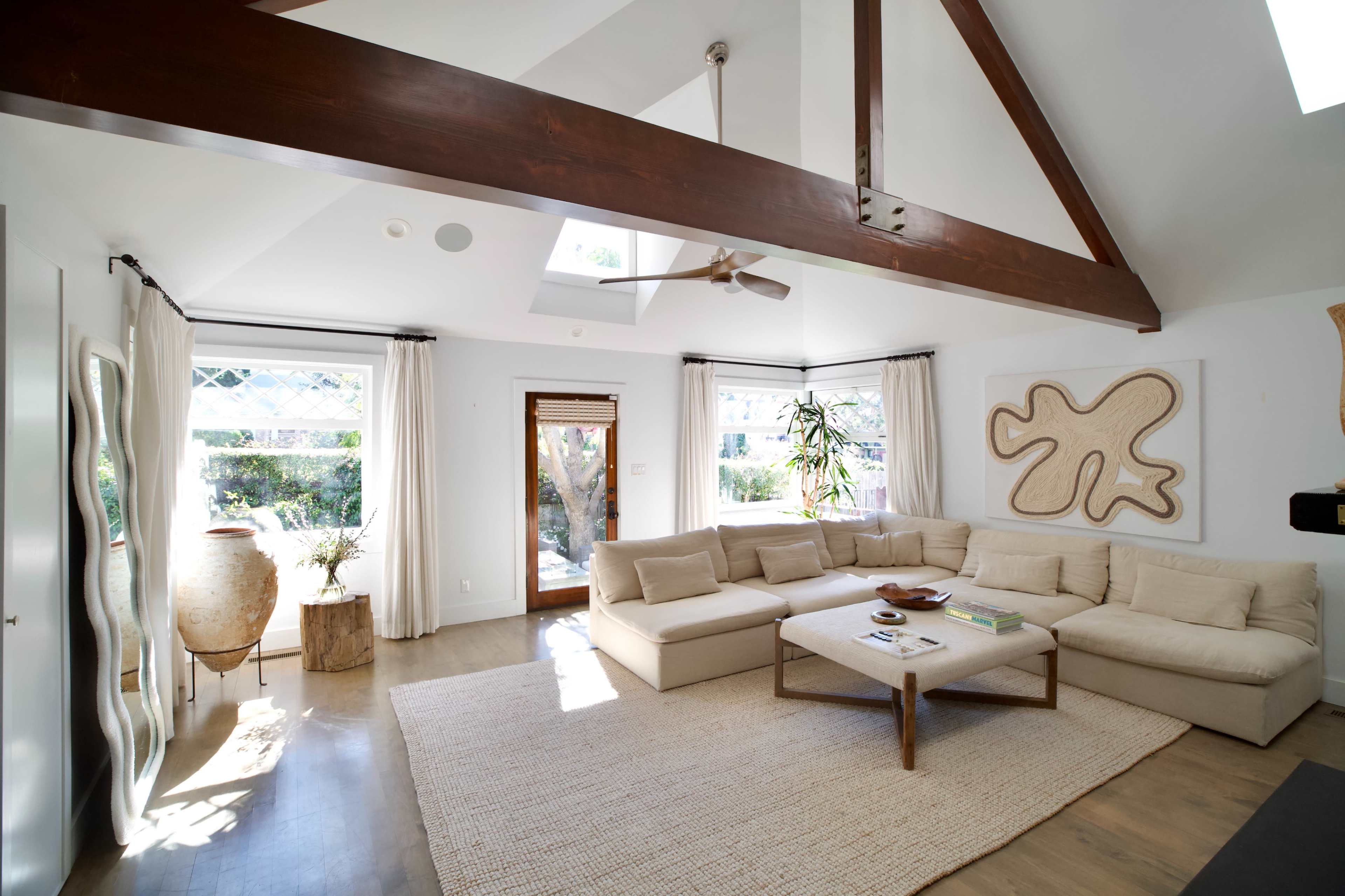 A spacious living room features a large sectional sofa, a coffee table, and natural light streaming in through windows and a skylight.
