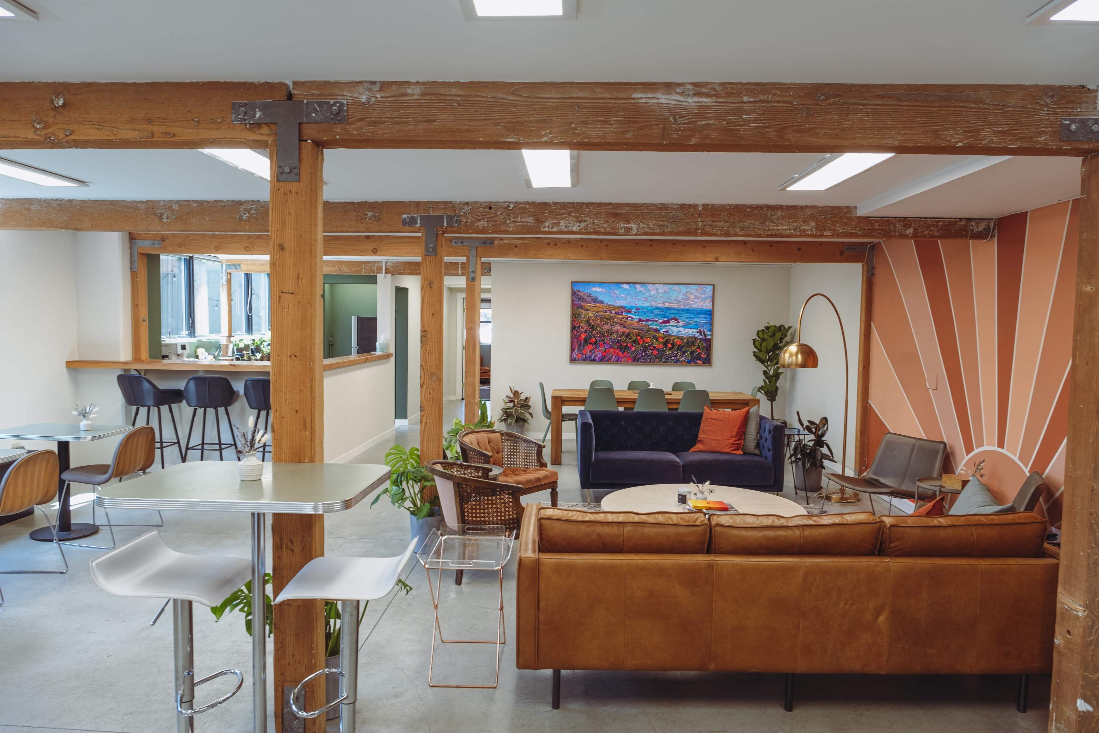 A modern interior space featuring wooden beams, comfortable seating areas, and a large artwork on the wall.