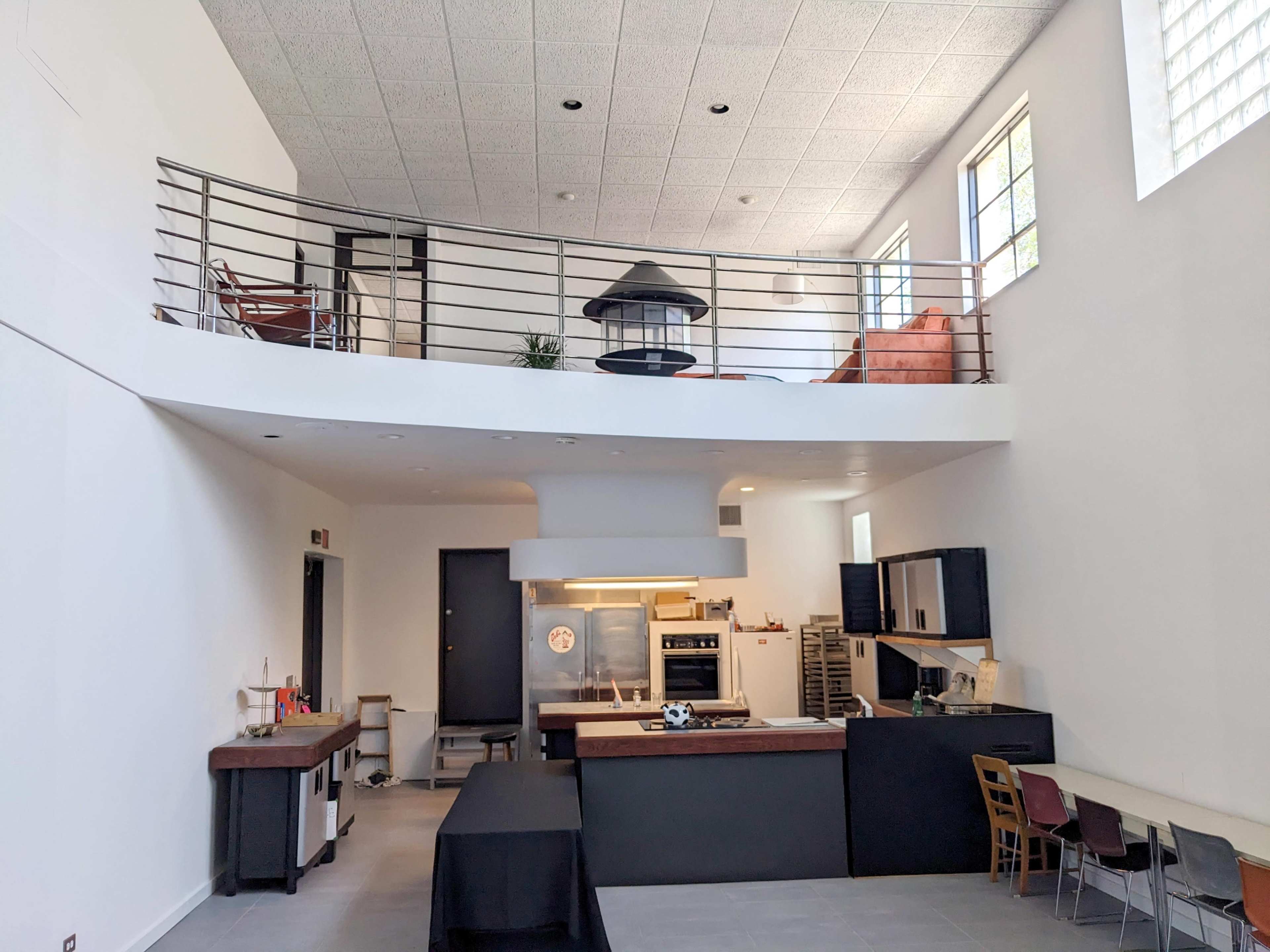A modern open-concept living space with a kitchen island, dining area, and a second floor balcony overlooking the main floor.