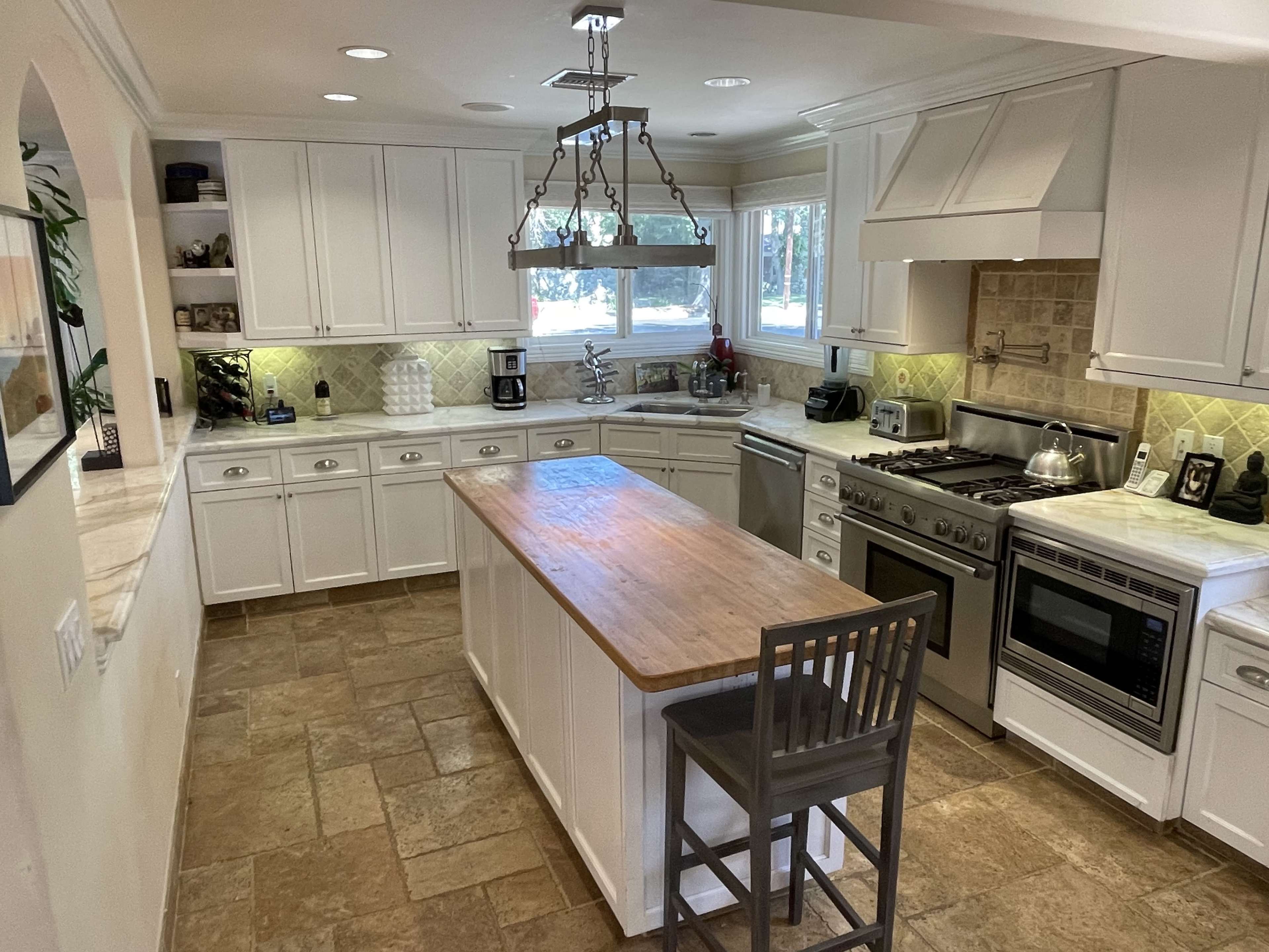 The kitchen features white cabinetry, a central island with a natural wood countertop, and stainless steel appliances.