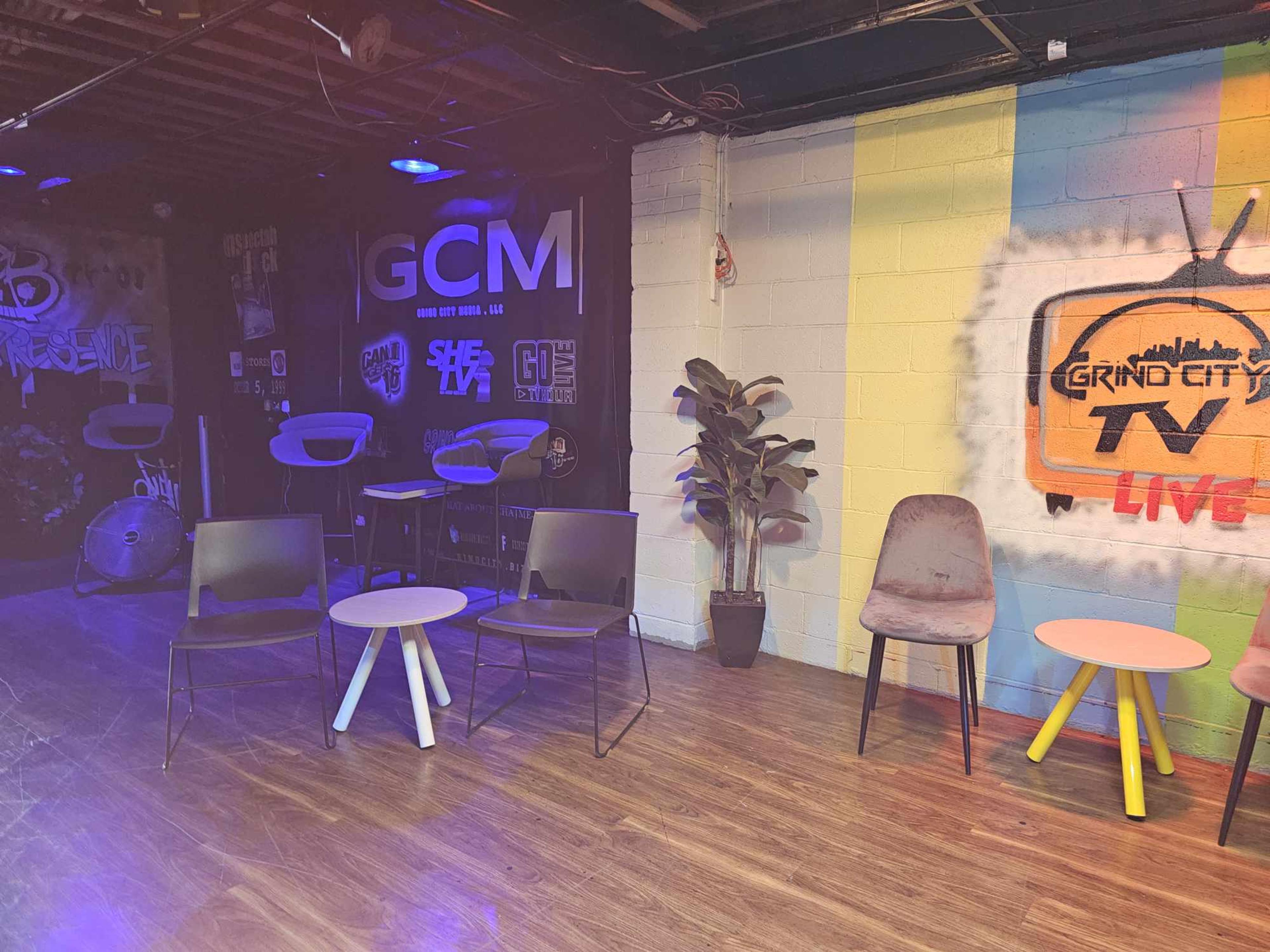 A lounge area with several chairs and small tables against a colorful graffiti wall.