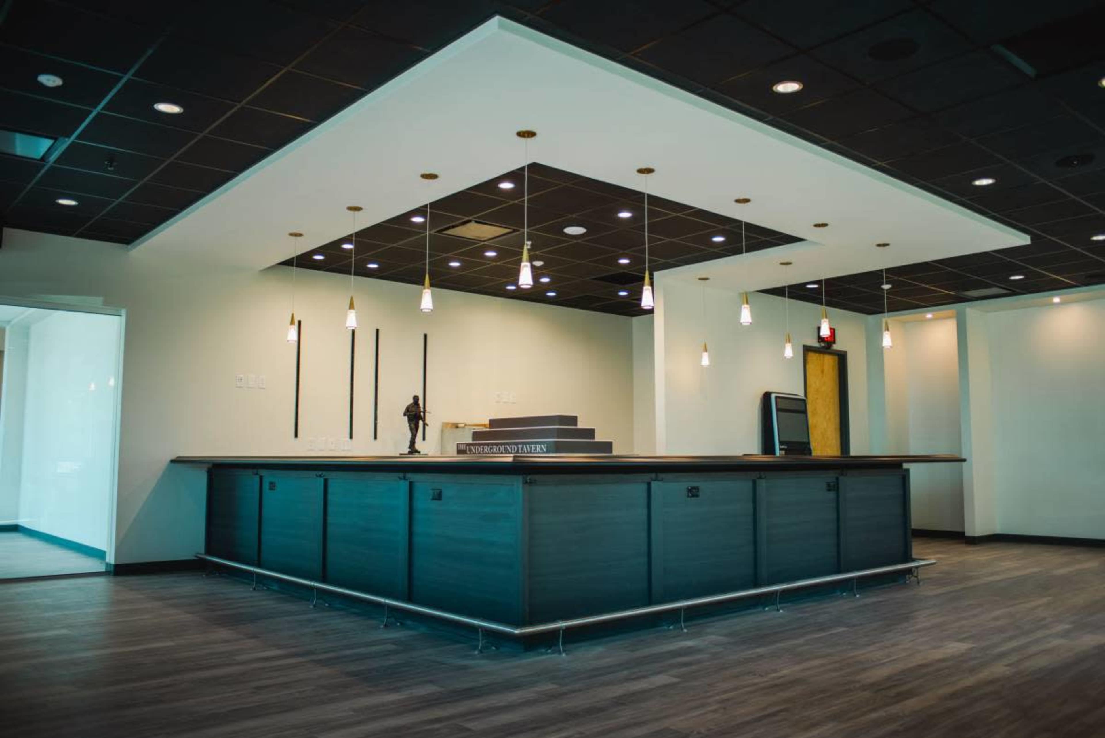 The image shows a modern, open office space with a large reception desk and pendant lighting.