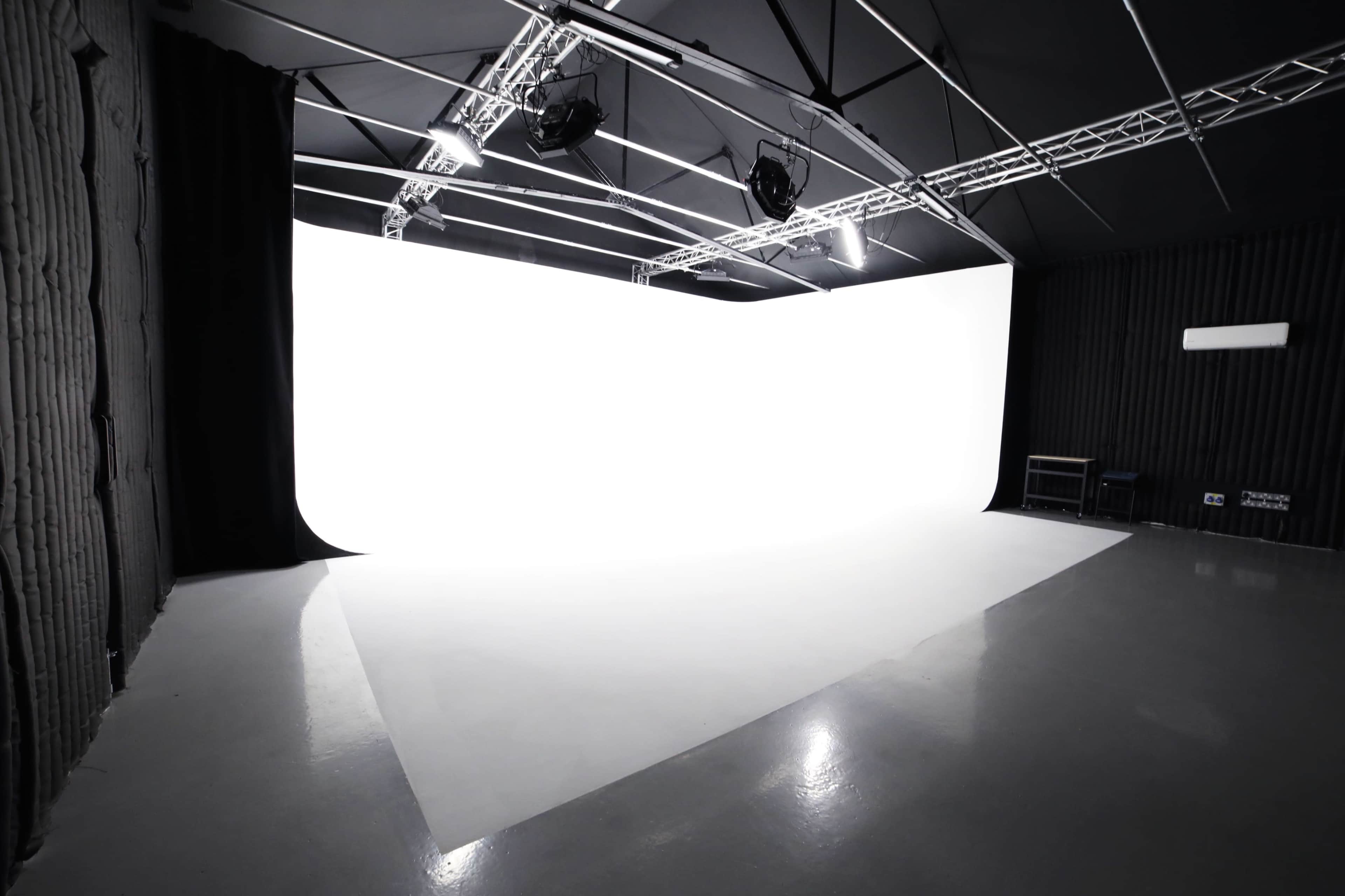 A photography studio with a large white backdrop and polished concrete floor under bright overhead lighting.