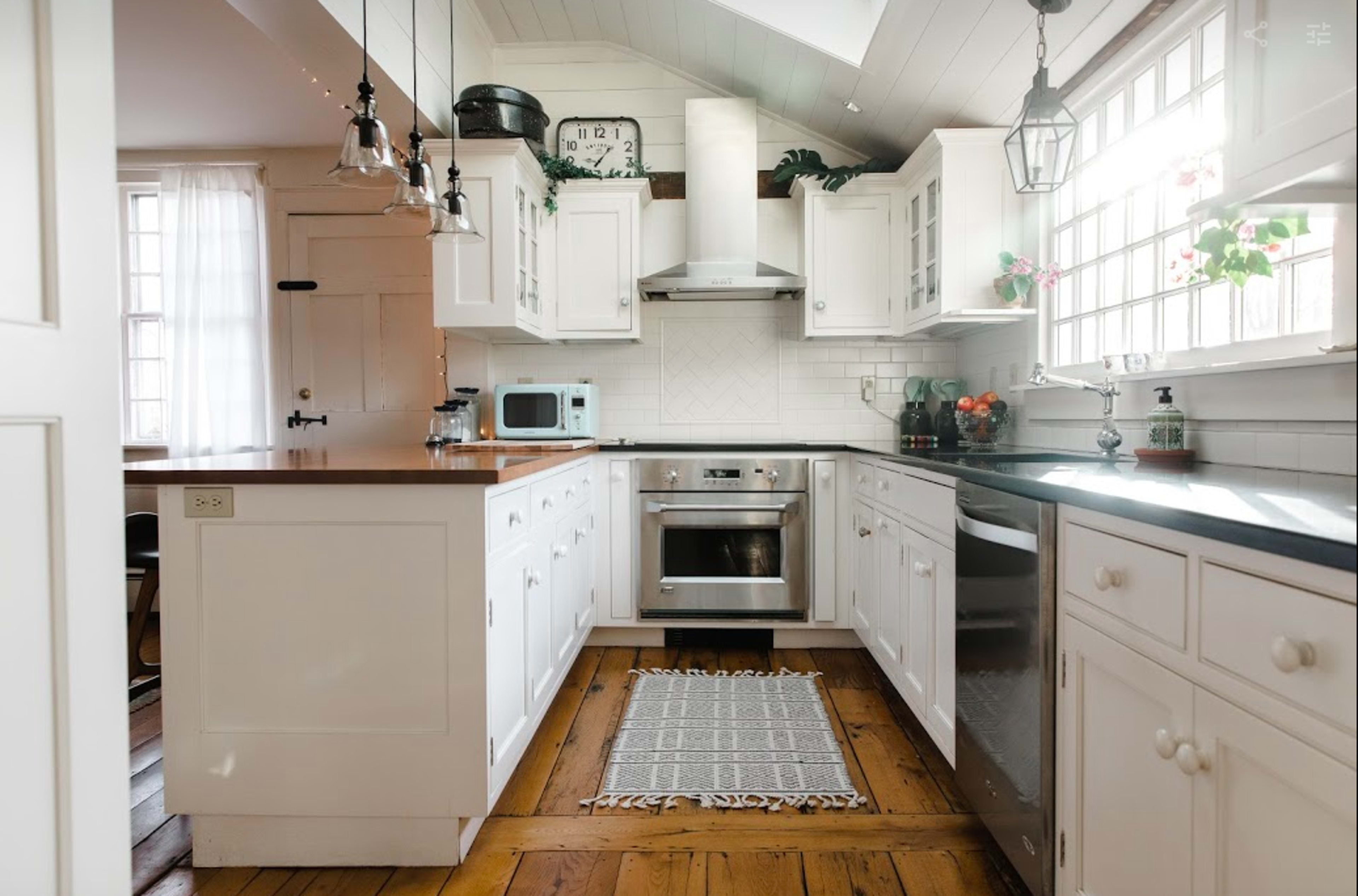 A bright kitchen features white cabinetry, a central island with a wooden countertop, and stainless steel appliances.