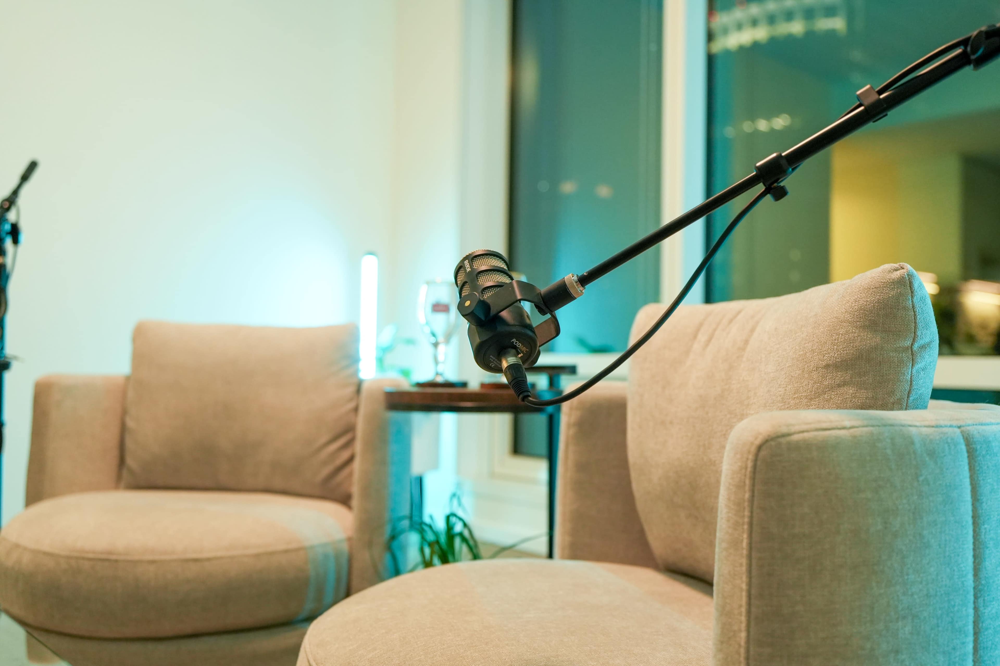 A pair of light gray upholstered chairs are positioned next to a small table with a glass and a microphone mounted on a stand.