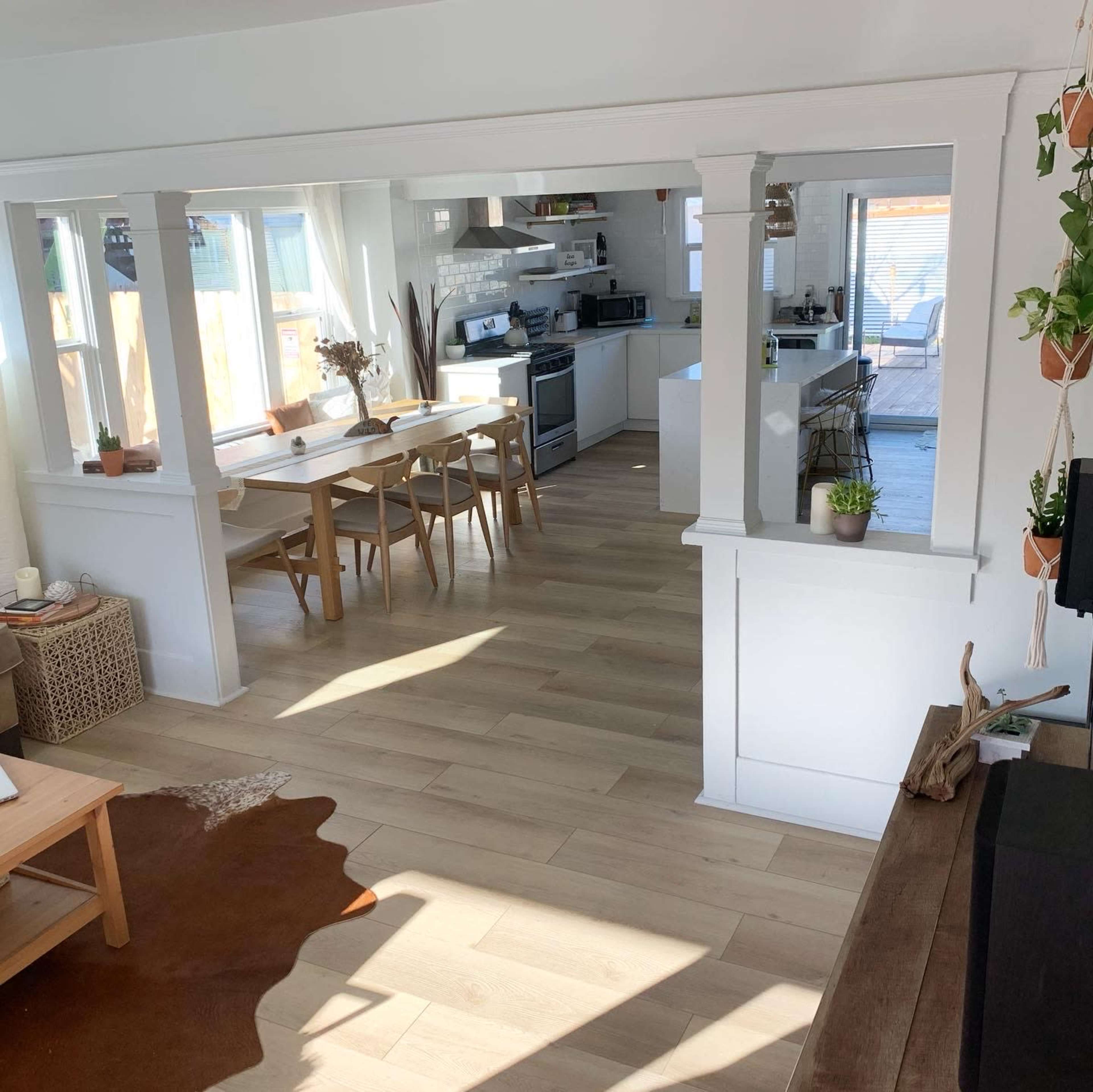 A bright, open-plan kitchen and dining area with wooden flooring, a dining table, and large windows.