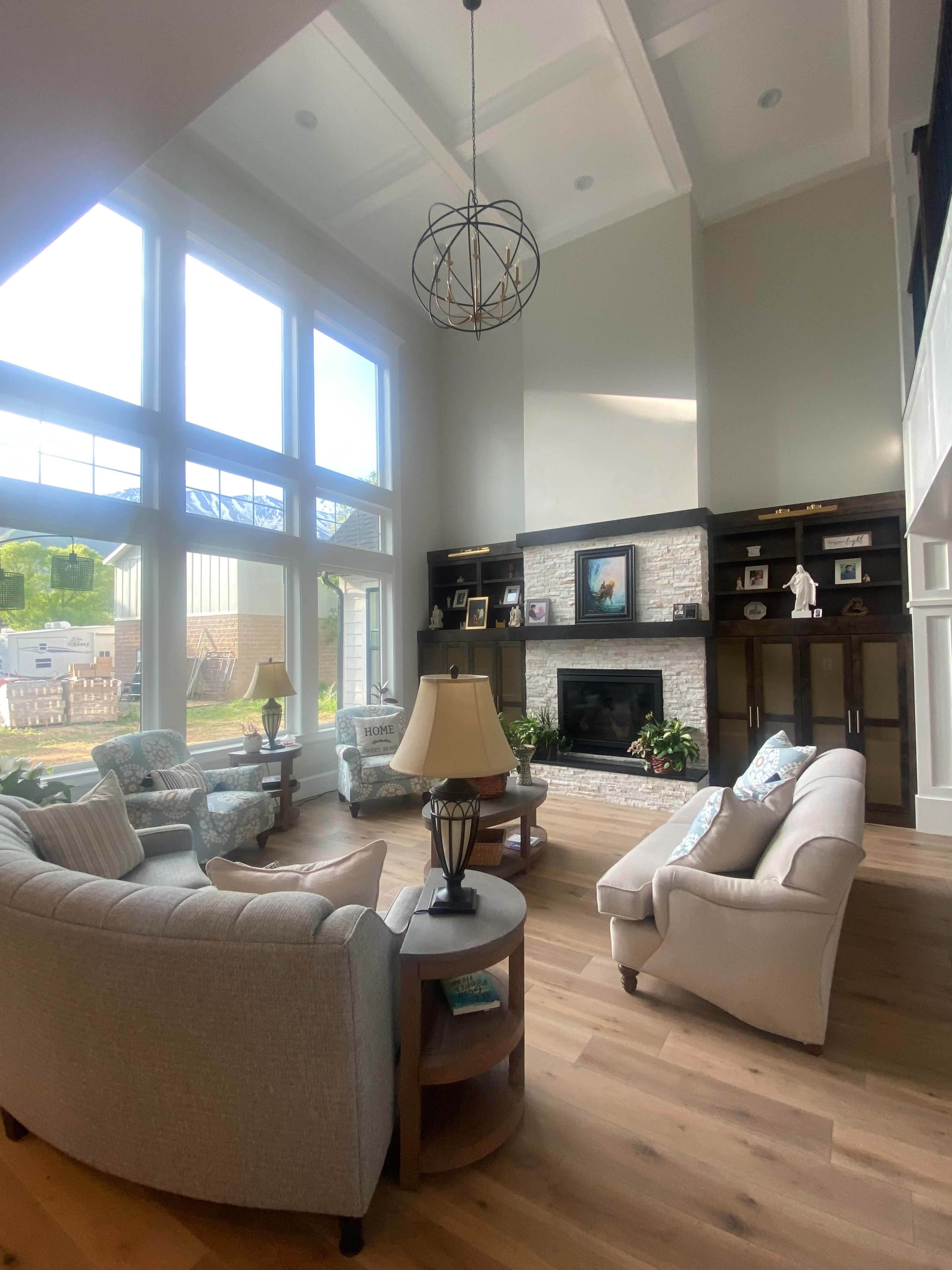 The spacious living room features large windows, a stone fireplace, and a mix of seating options arranged around a coffee table.