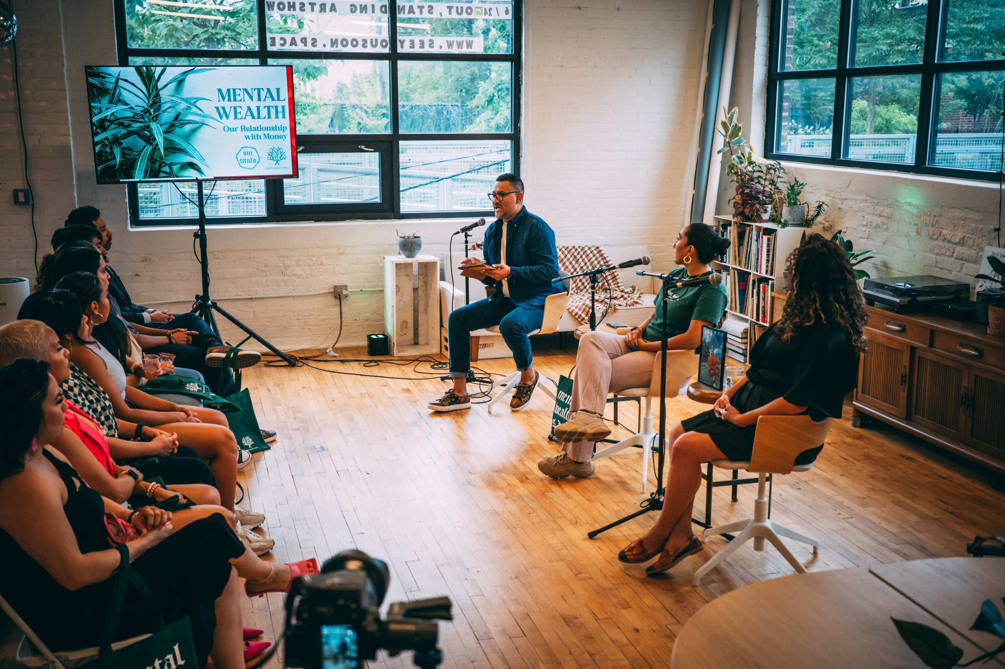 A panel discussion on mental health takes place in a well-lit room with an audience seated in front of the speakers.