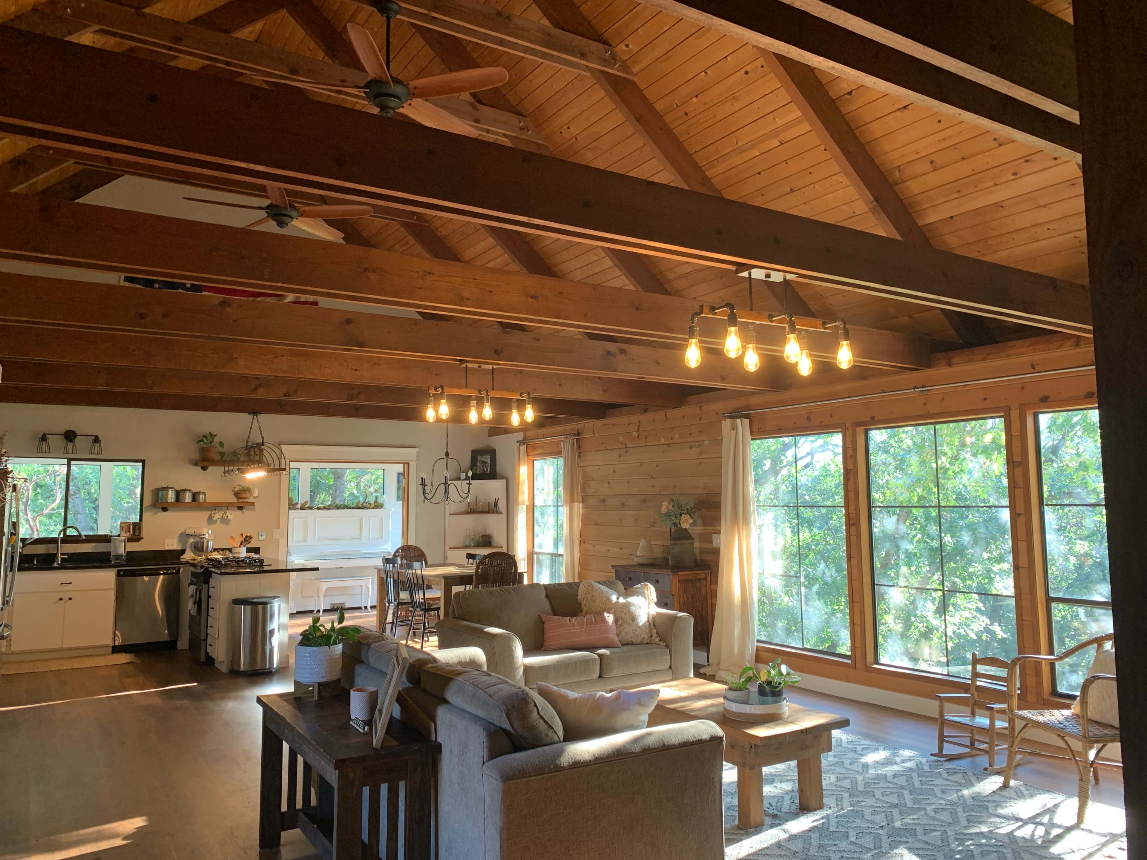 A spacious, rustic living area with a wooden ceiling, large windows, and a comfortable seating arrangement.