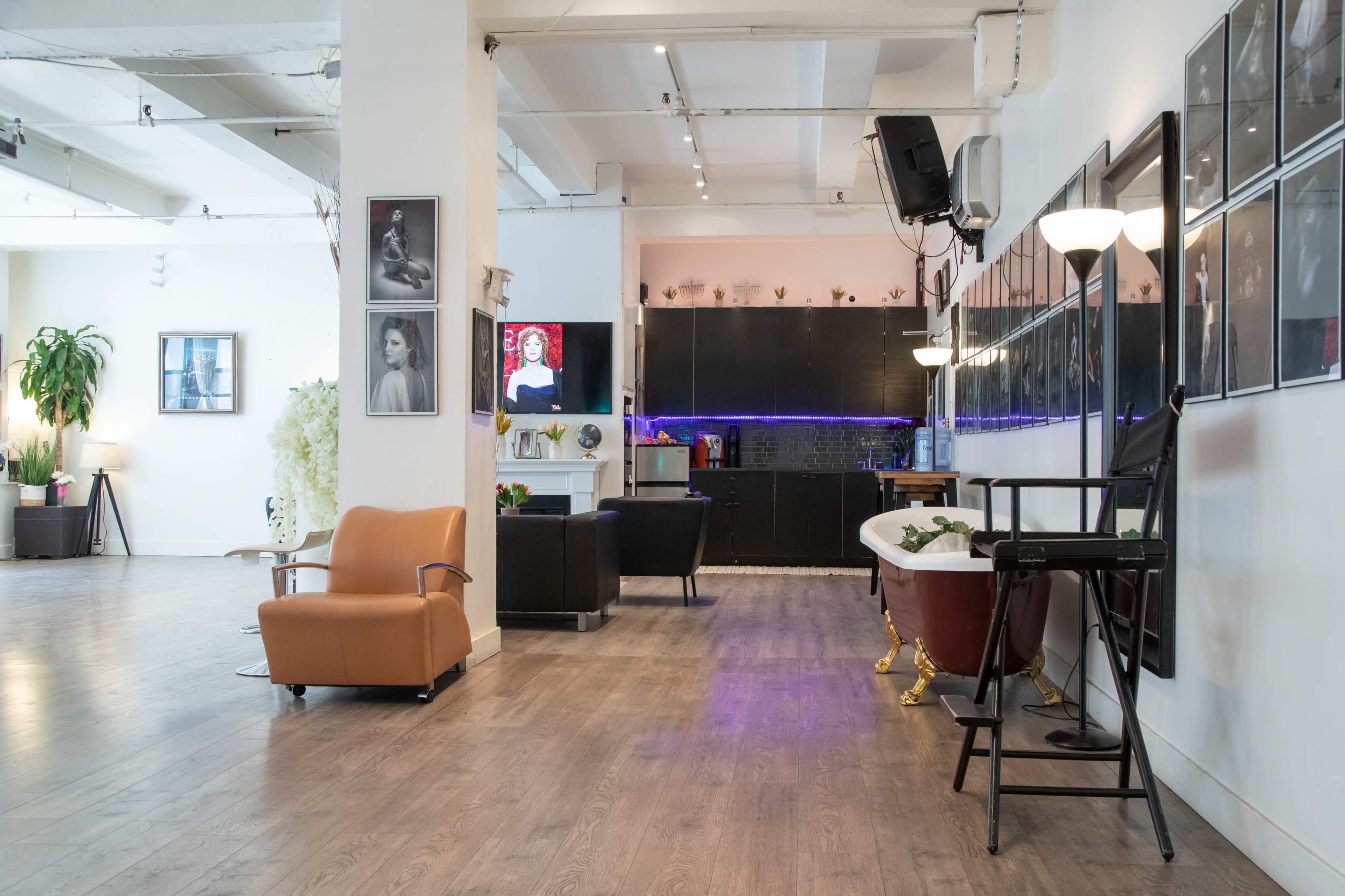 The interior features a spacious, modern living area with various seating options, a bathtub, and a wall adorned with framed photographs.