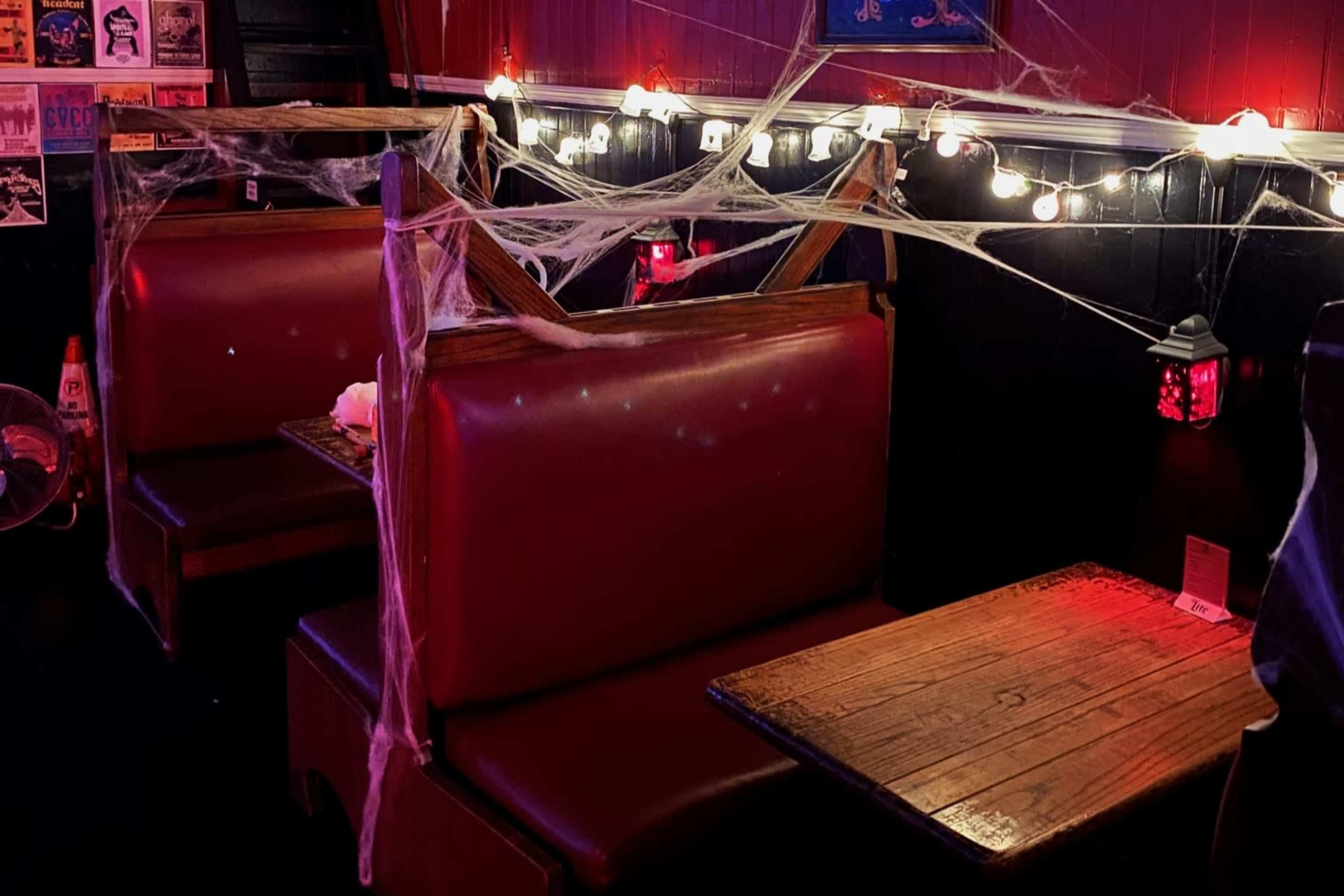 A dimly lit restaurant booth decorated with cobwebs and string lights.