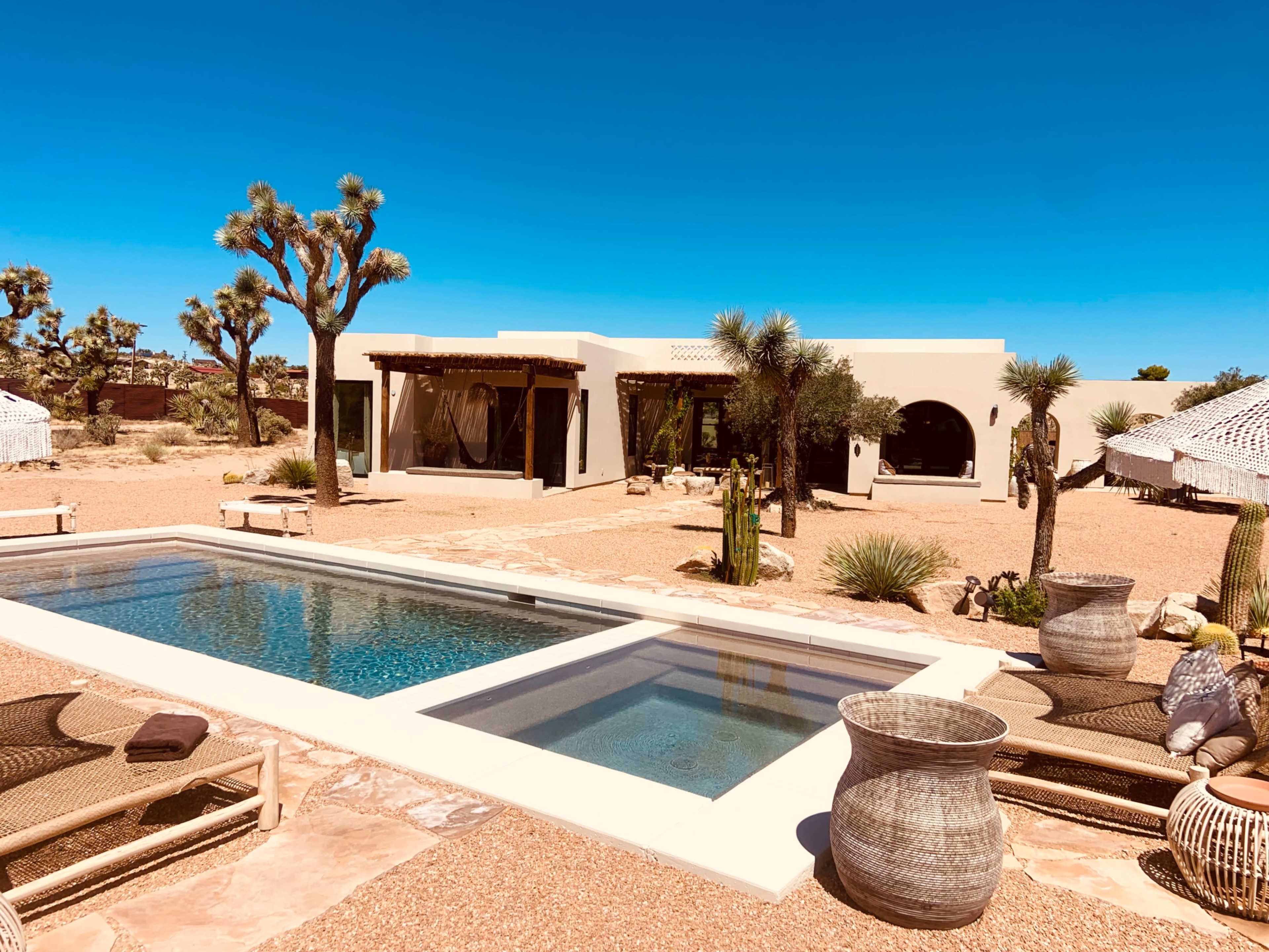 A modern desert home featuring a pool, surrounded by cacti and landscaped with native plants.