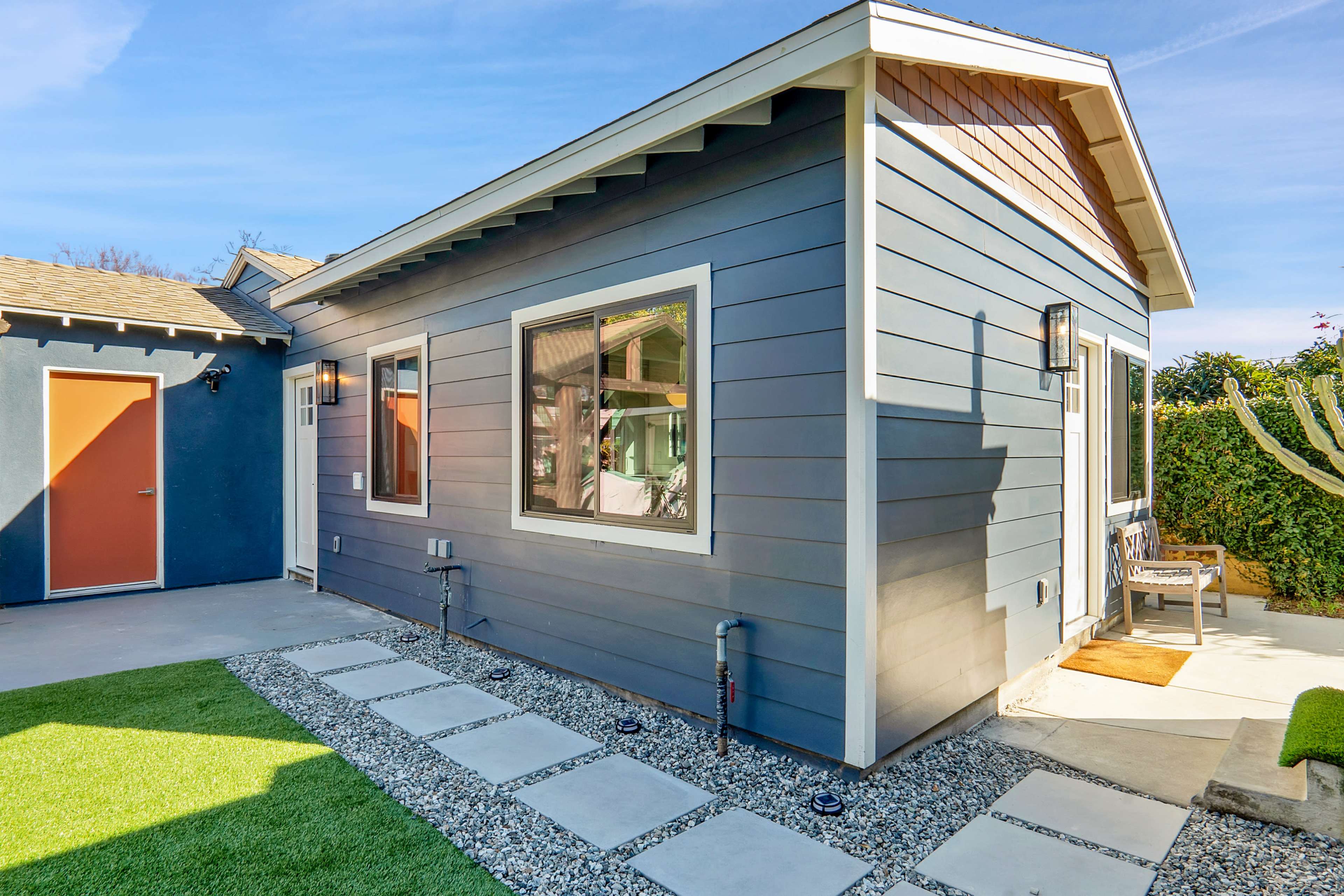 The exterior of a blue house with a gravel walkway and a small patio area.
