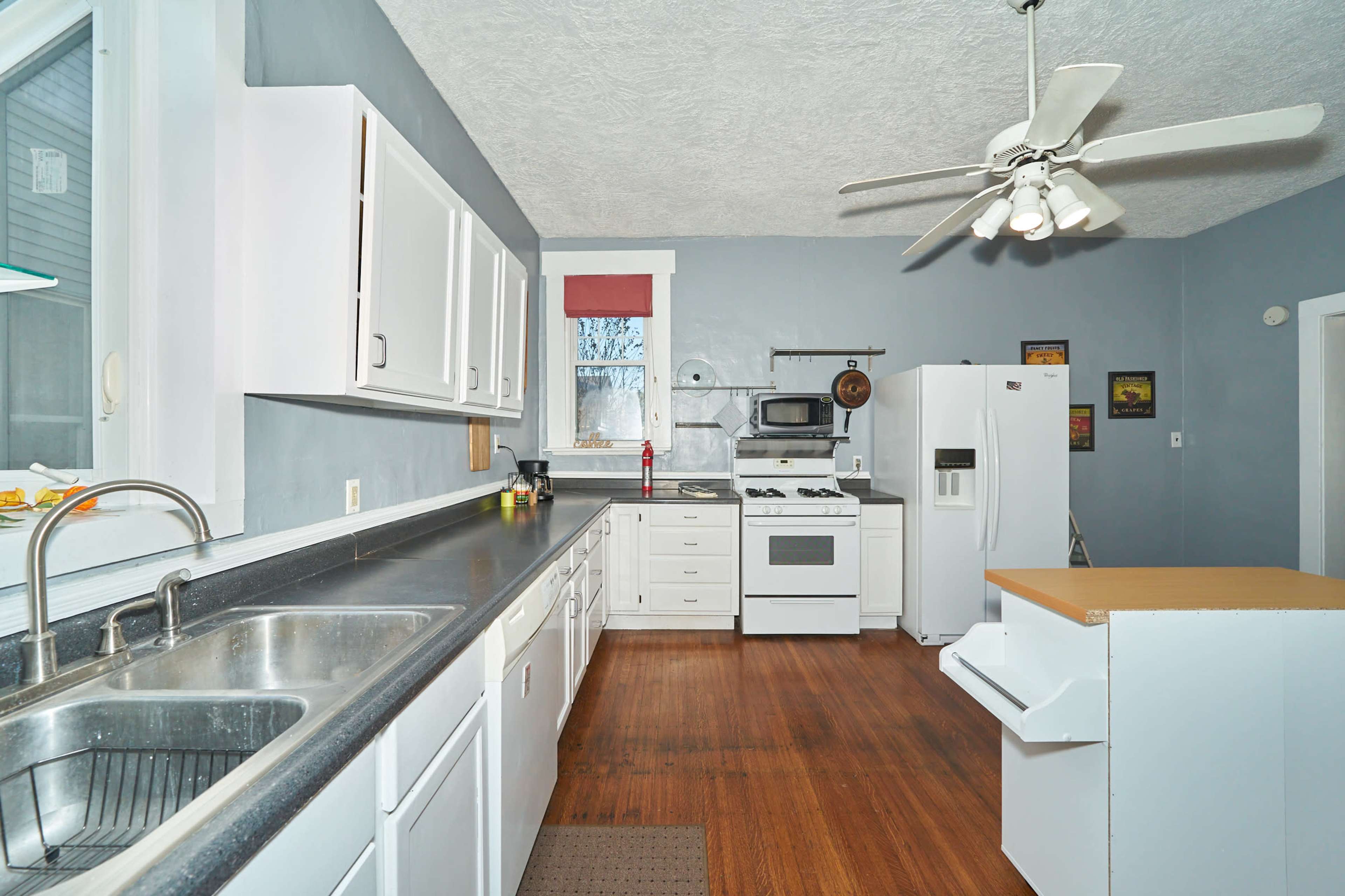 A kitchen with white cabinetry, a black countertop, and appliances, including a refrigerator and stove, arranged along one wall.