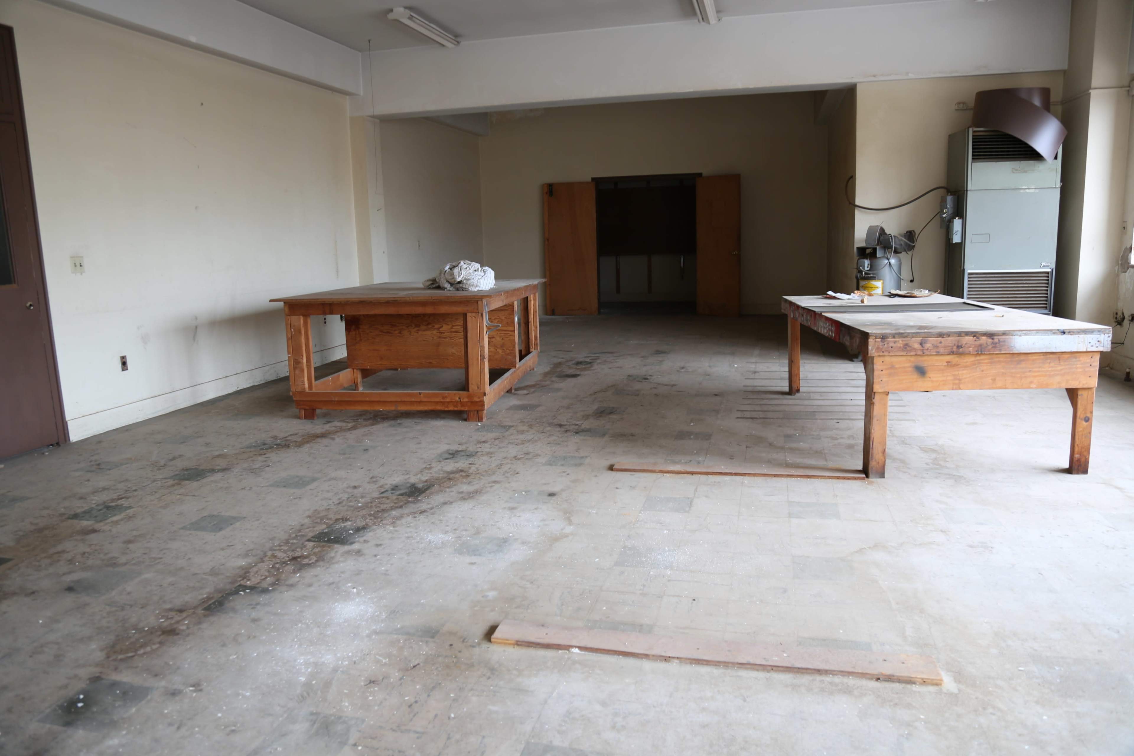 An empty room with two wooden tables and a partially visible cabinet against the wall.
