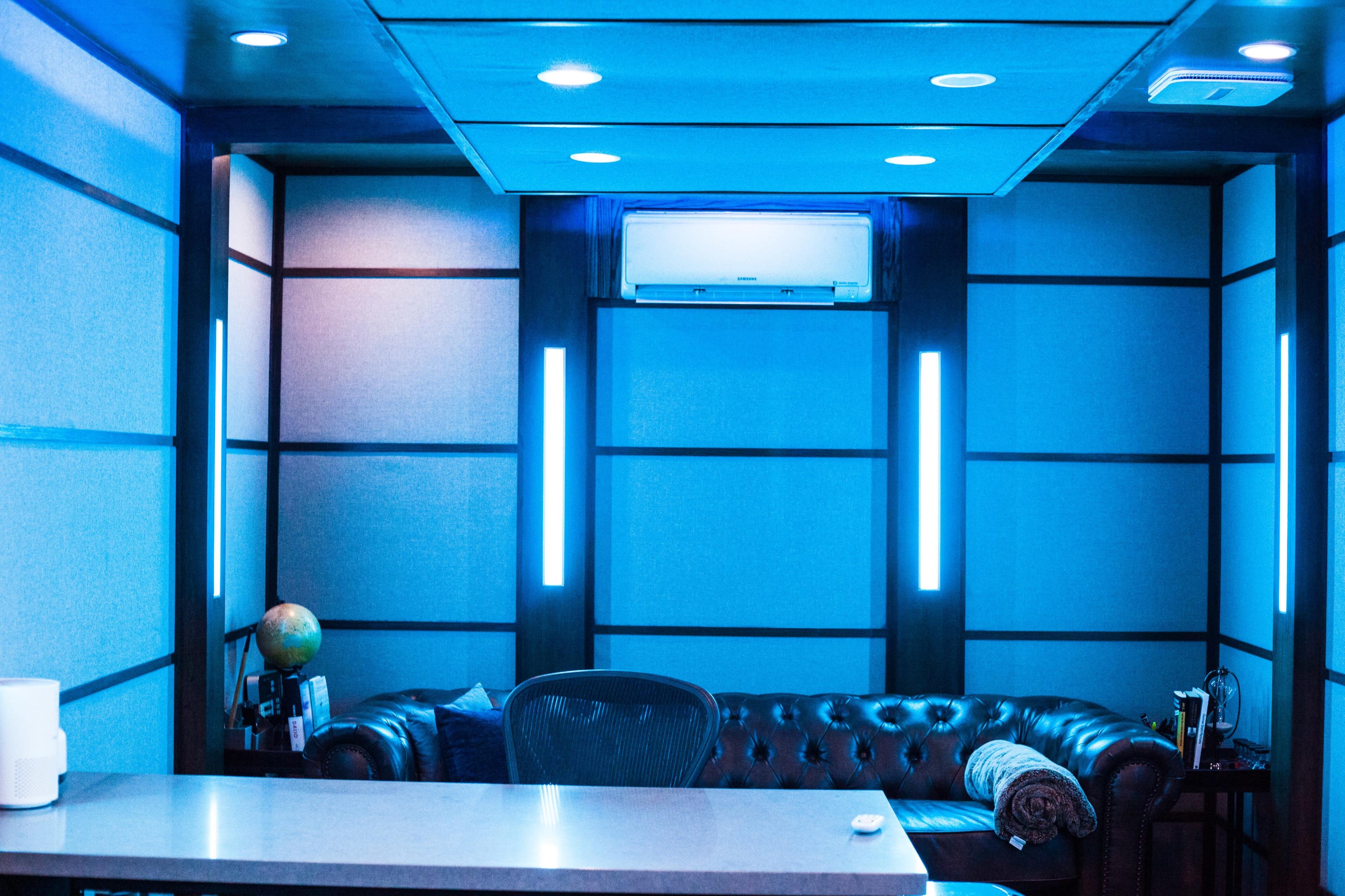 A modern waiting area with a leather couch, a globe, and blue accent lighting on the walls.