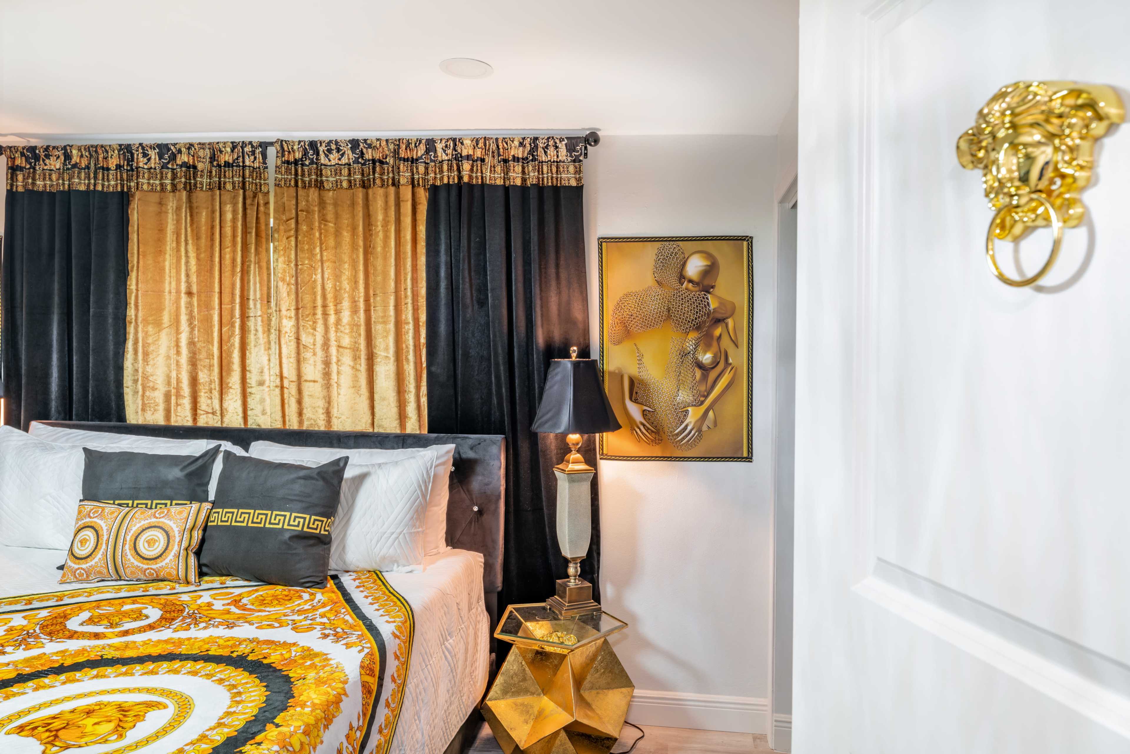 A stylishly decorated bedroom featuring a bed with a patterned blanket, a bedside lamp, and a framed artwork on the wall.