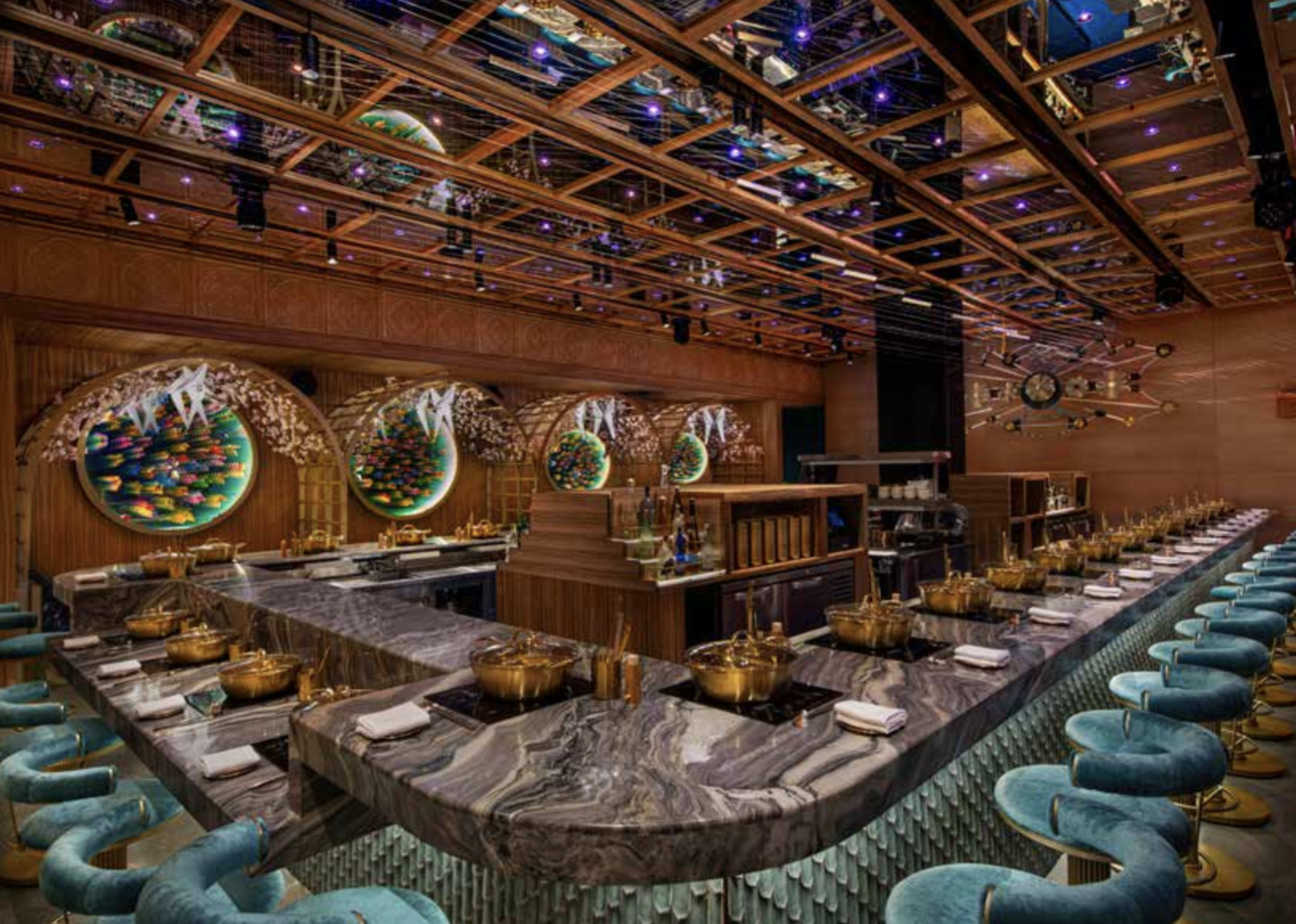 The image depicts a modern restaurant interior featuring a long marble bar with seating, adorned with artistic wall decorations and a ceiling featuring intricate lighting.