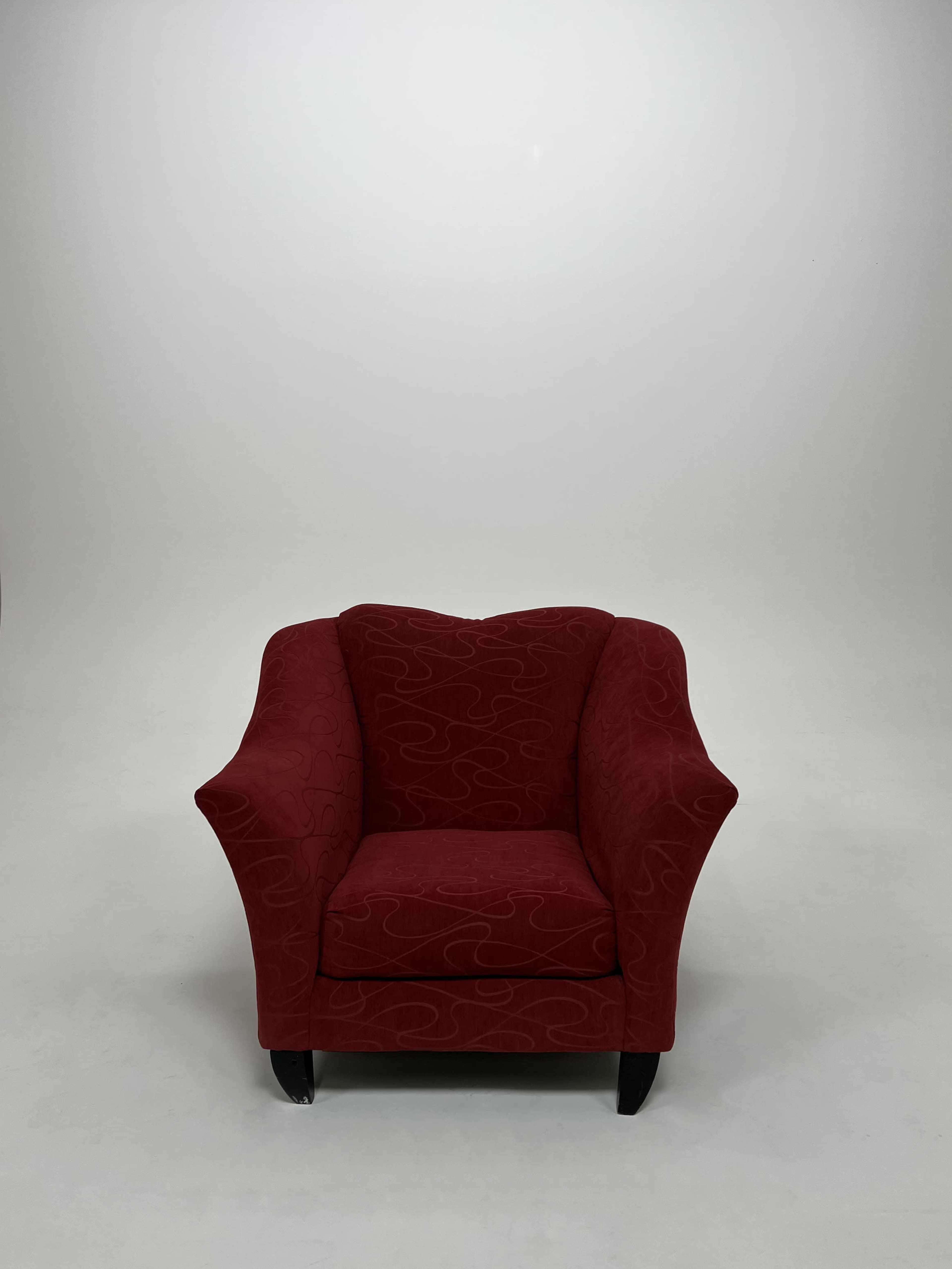 A red upholstered armchair with a patterned fabric set against a plain white background.