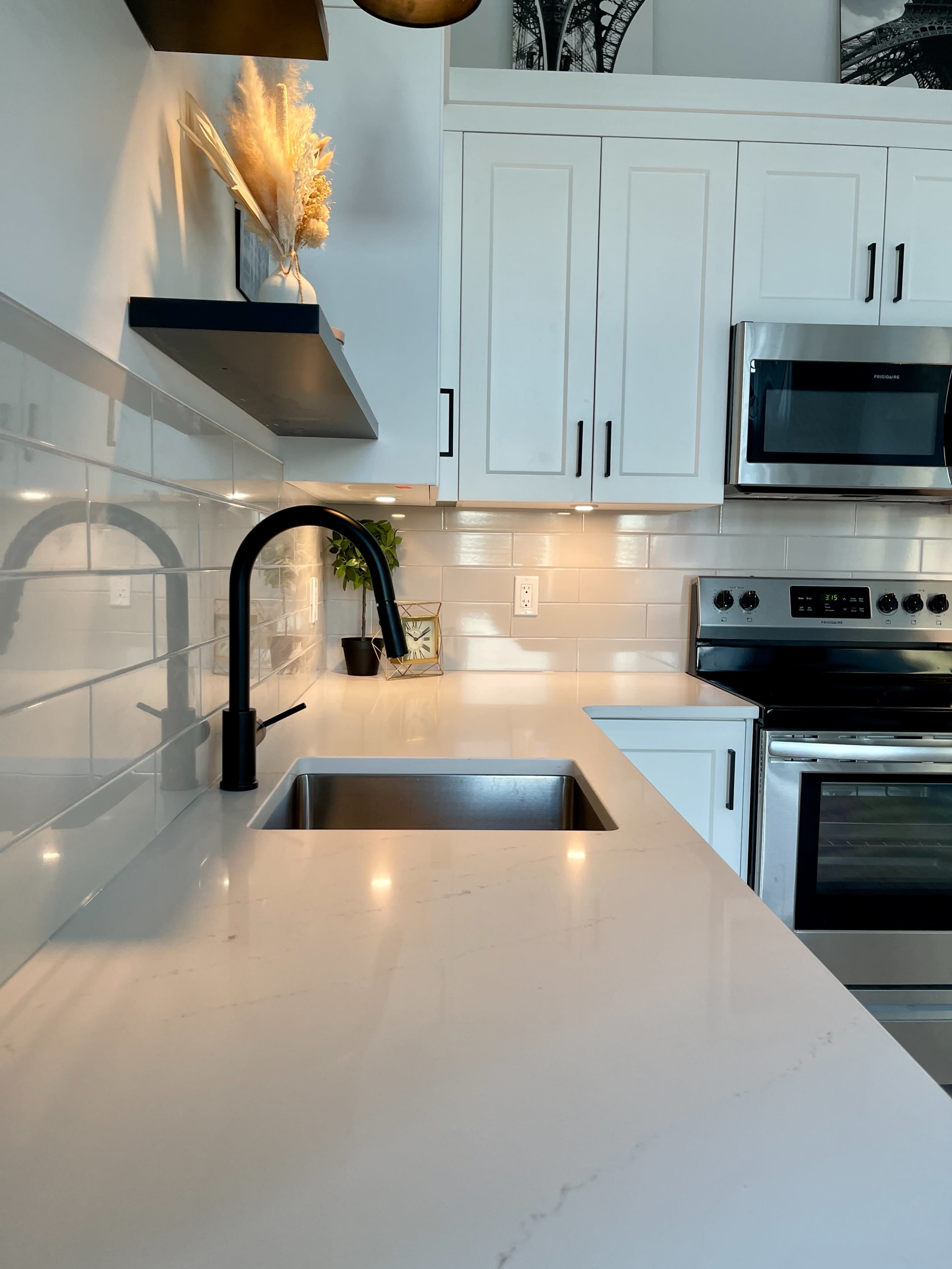 A modern kitchen with a sleek black faucet, white cabinetry, and stainless steel appliances.