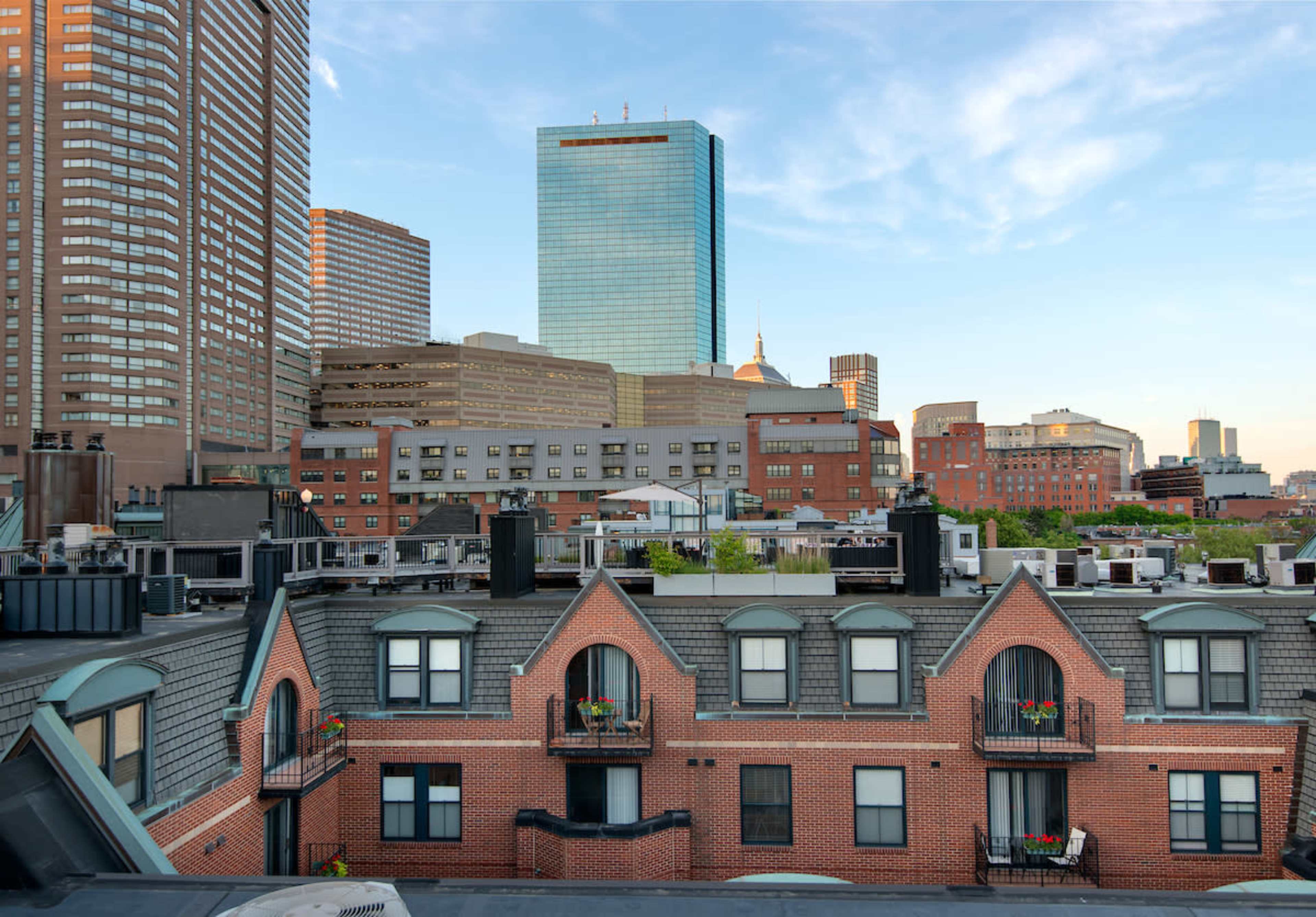 A city skyline with modern skyscrapers in the background and a row of brick buildings with balconies in the foreground.