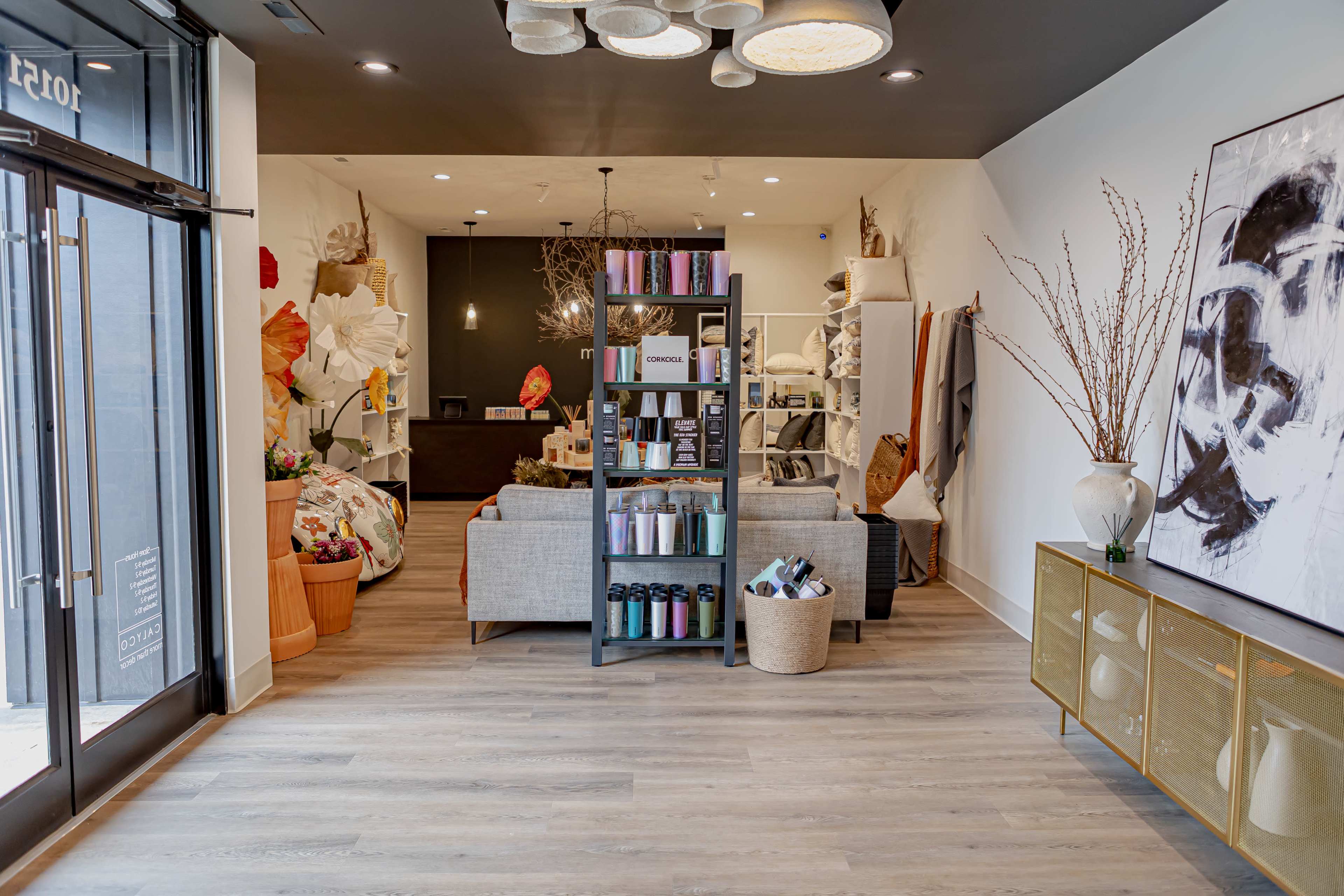 A modern retail space with a seating area, decorated shelves, and various home goods displayed prominently.