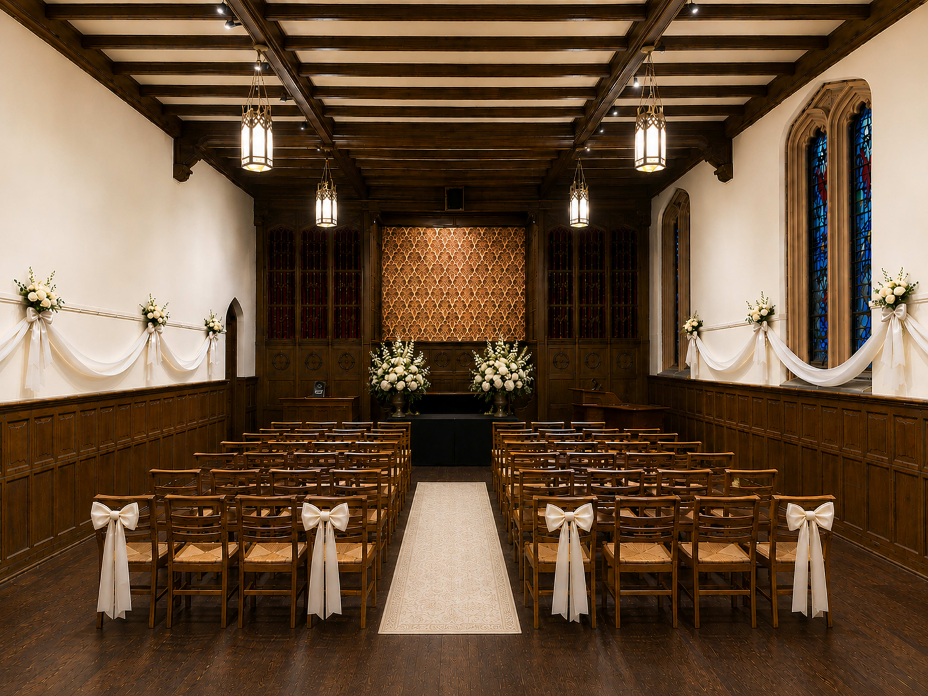 The image shows a prepared wedding ceremony space with rows of wooden chairs adorned with white bows, facing a decorated altar against a textured wall.