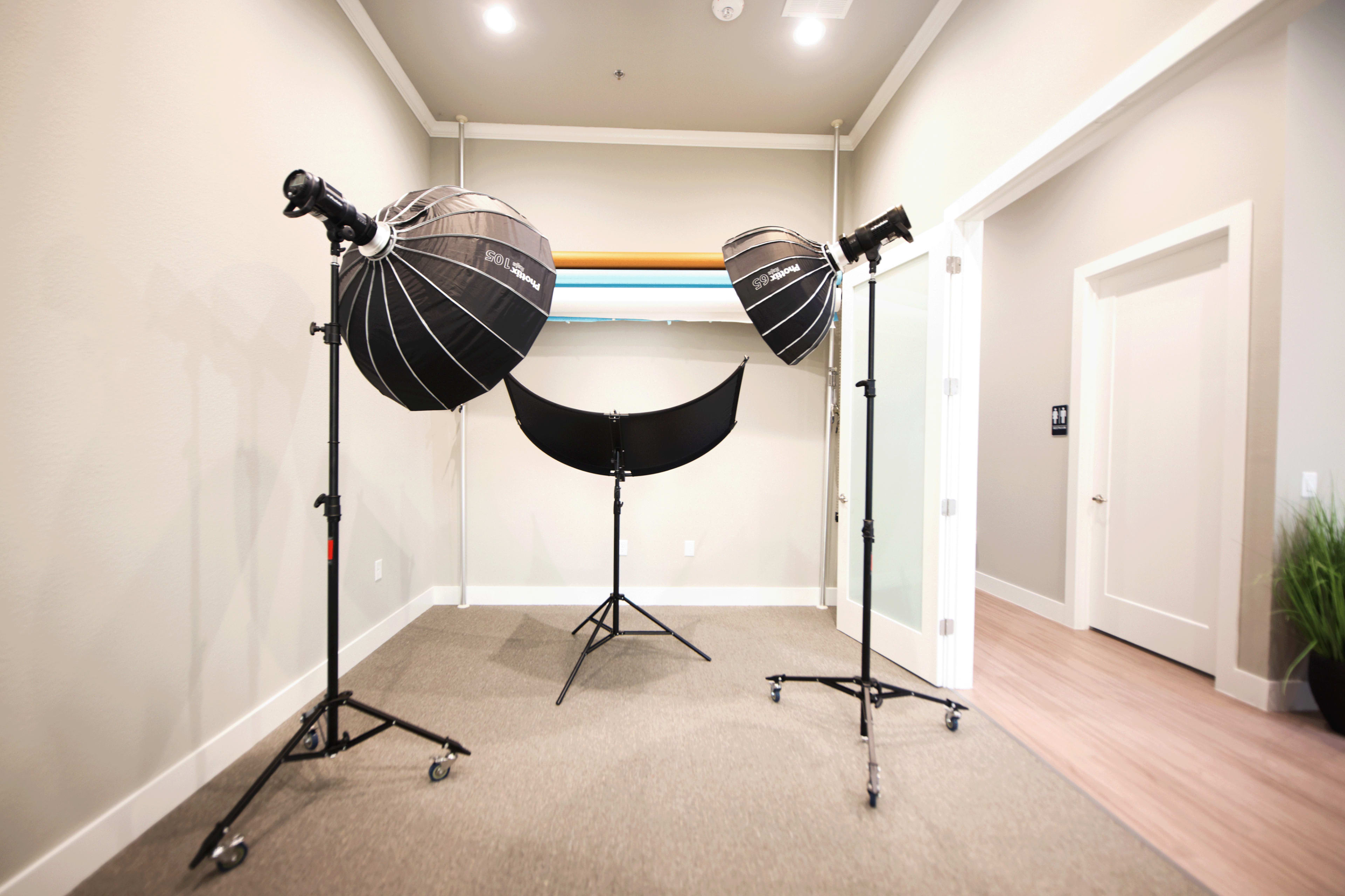 The room features two softbox lights on stands directed at a black backdrop that is supported by a stand.