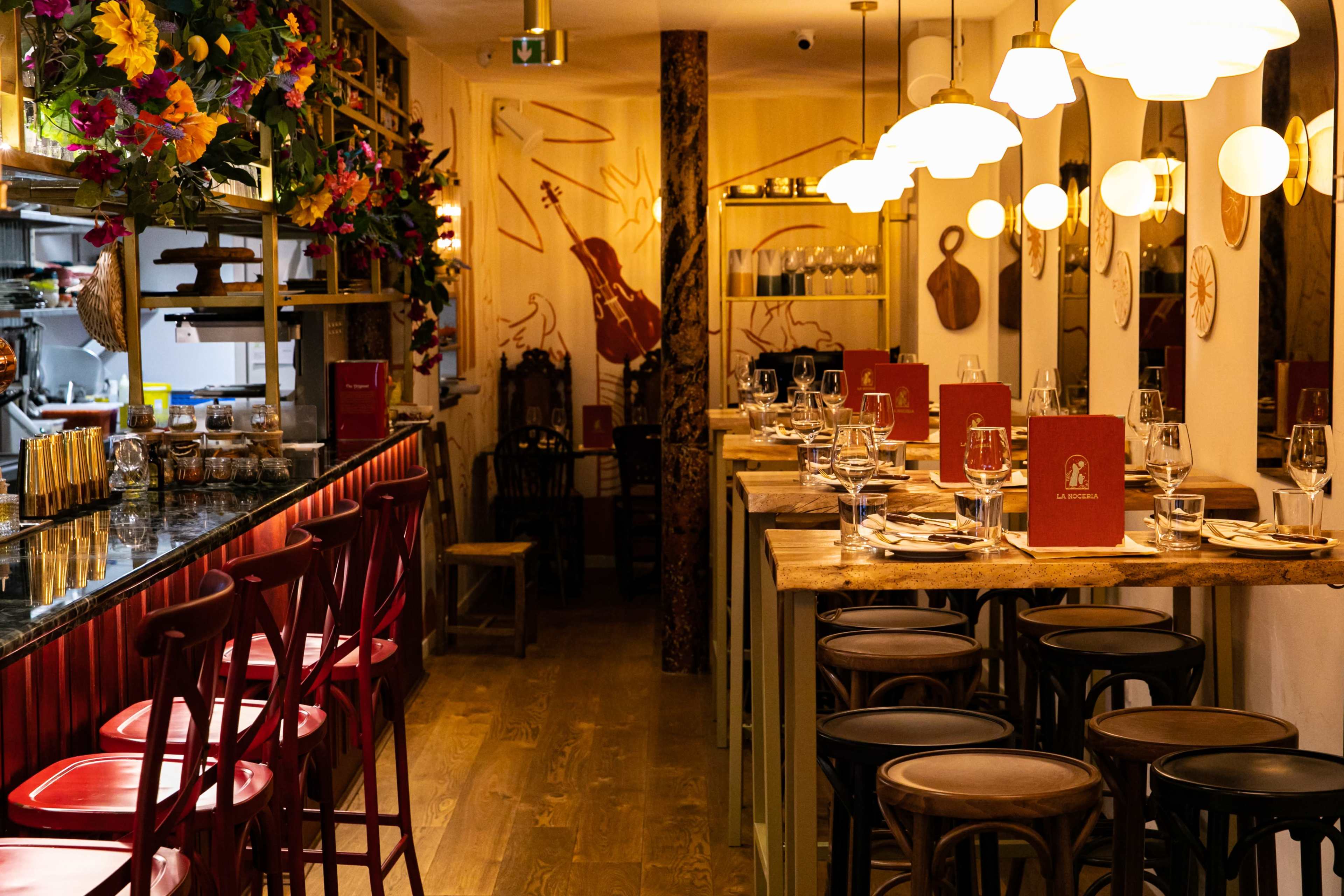 A restaurant interior featuring a combination of bar seating and tables, adorned with colorful decorations and vibrant lighting.