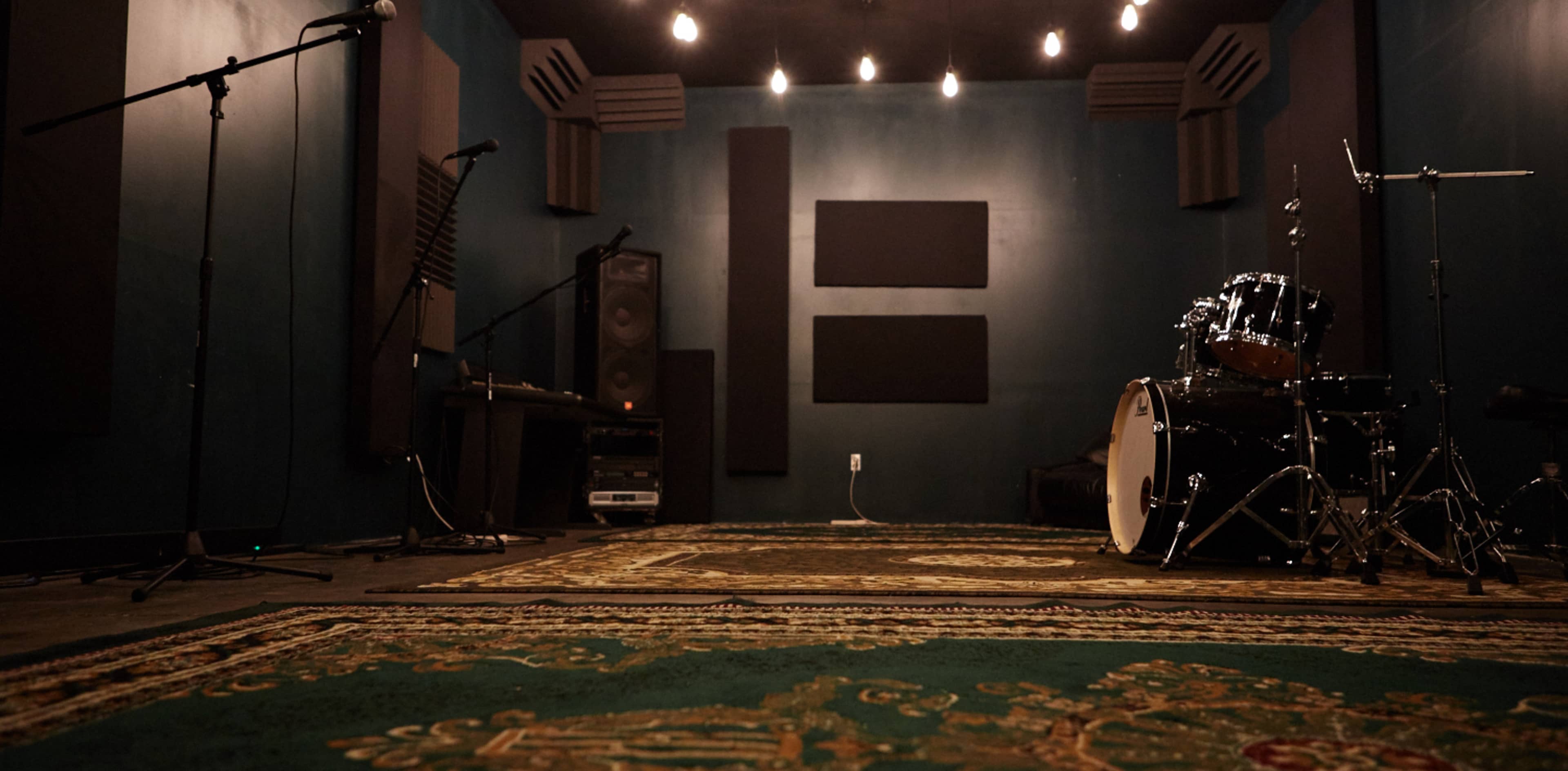 A soundproof recording studio with microphones, a drum set, and acoustic panels on the walls.