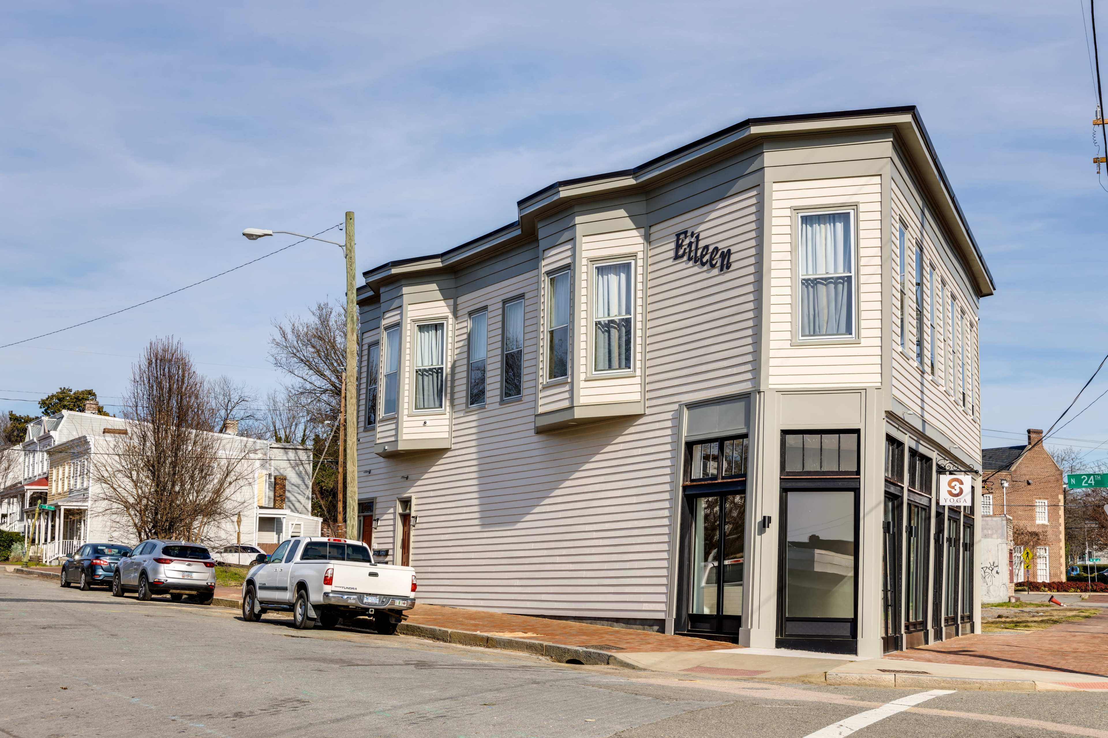 A corner building with the name "Eileen" displayed on its side, surrounded by parked cars on a street.