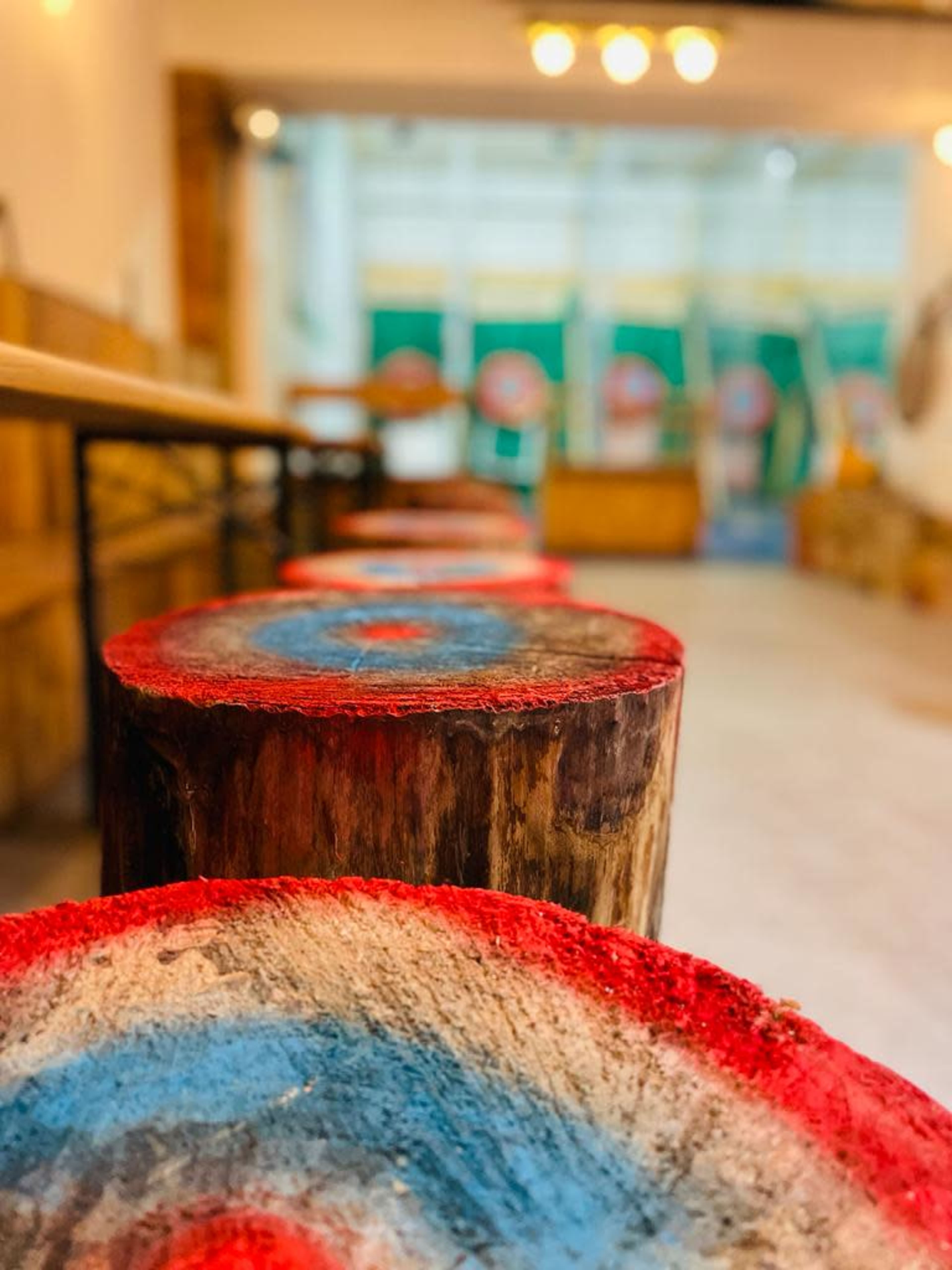 A line of wooden targets with painted blue and red bullseyes, positioned in an indoor axe-throwing venue.