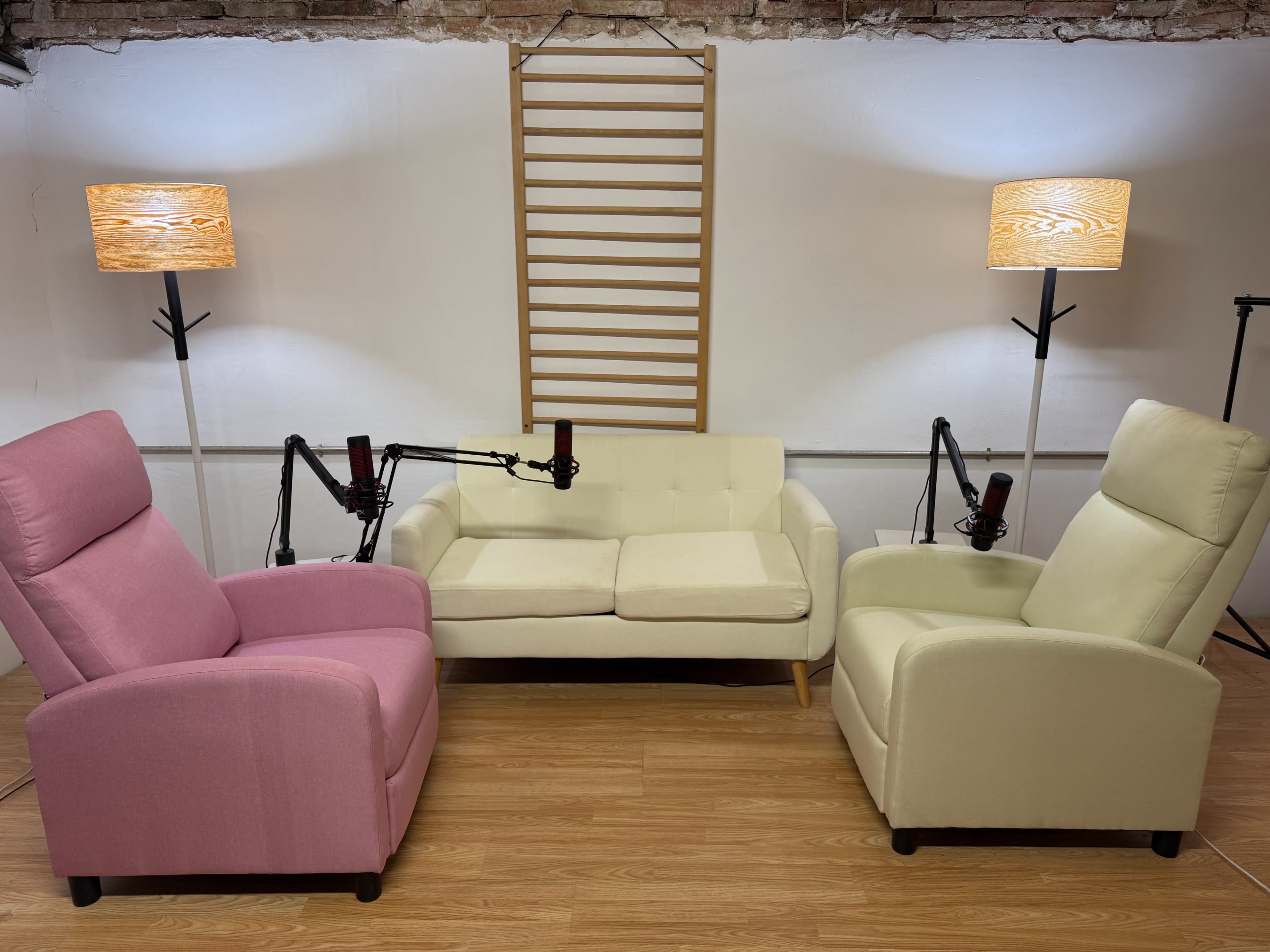 The image shows a cozy seating area with a pink recliner, a light green recliner, and a cream-colored sofa, all arranged around a wooden ladder and two floor lamps.