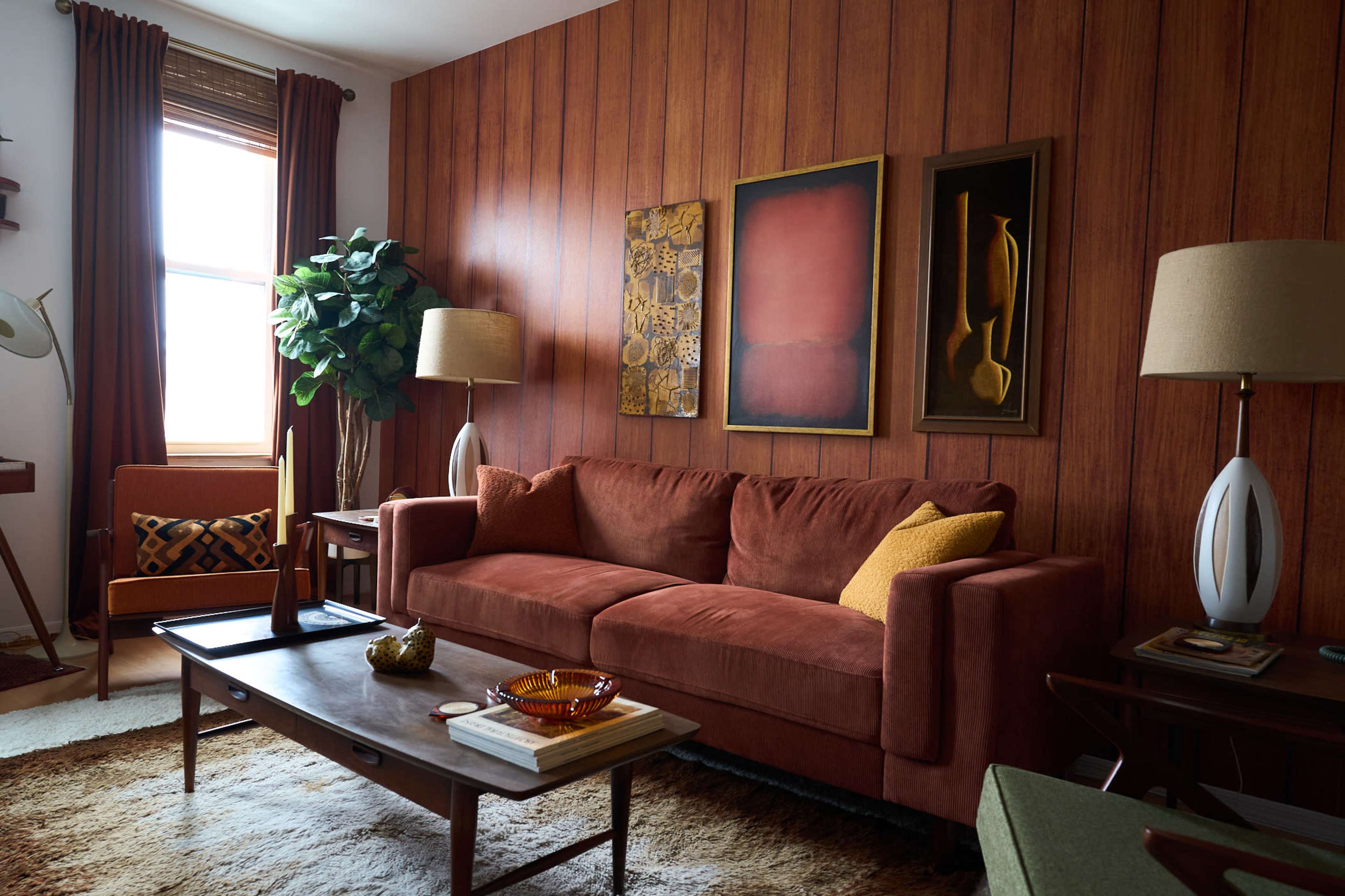 The image shows a retro-style living room featuring a brown sofa, wooden paneled walls, and various decorative elements including paintings and lamps.