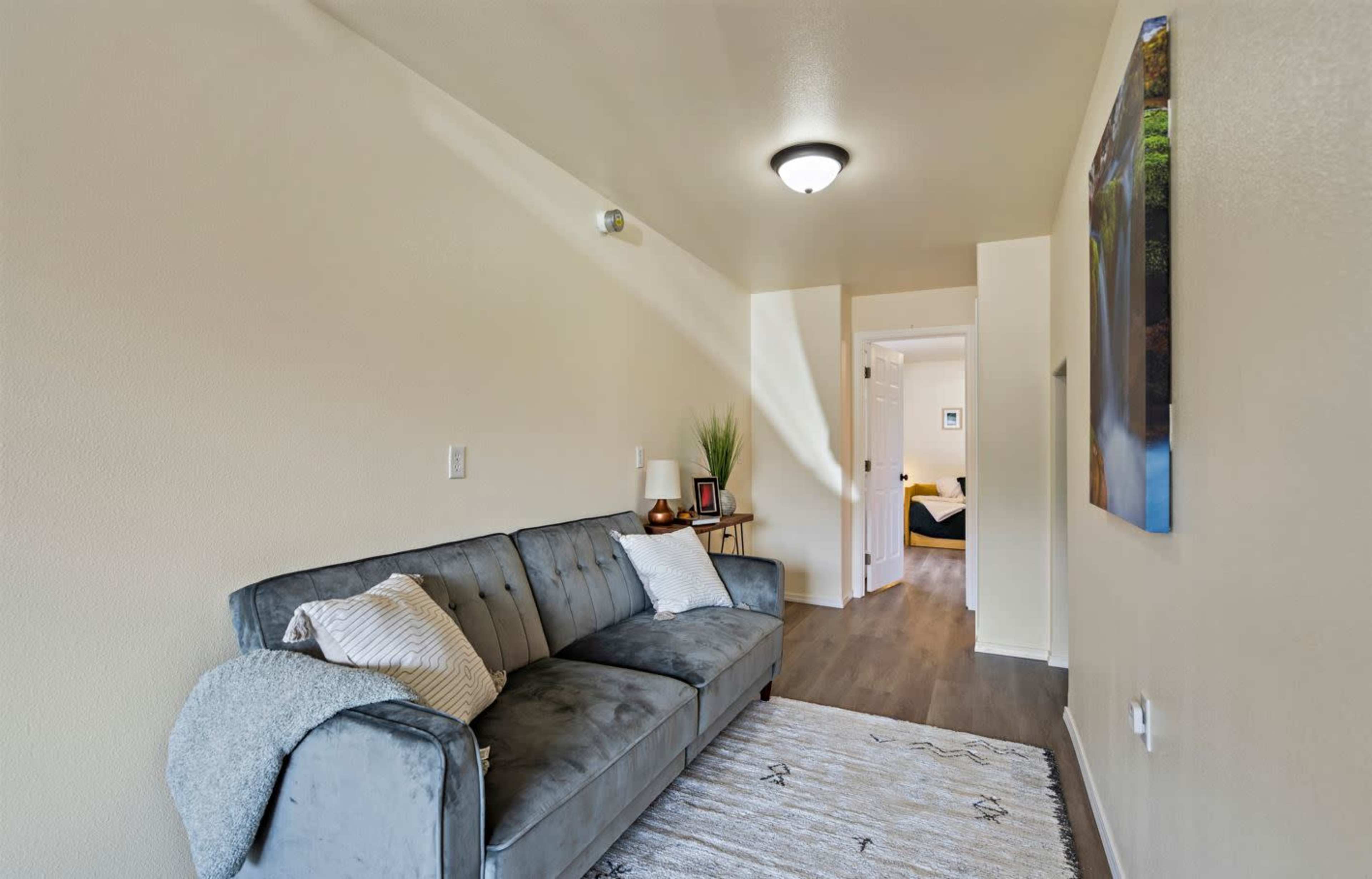 A living room with a gray sofa, a rug, and a doorway leading to another room.