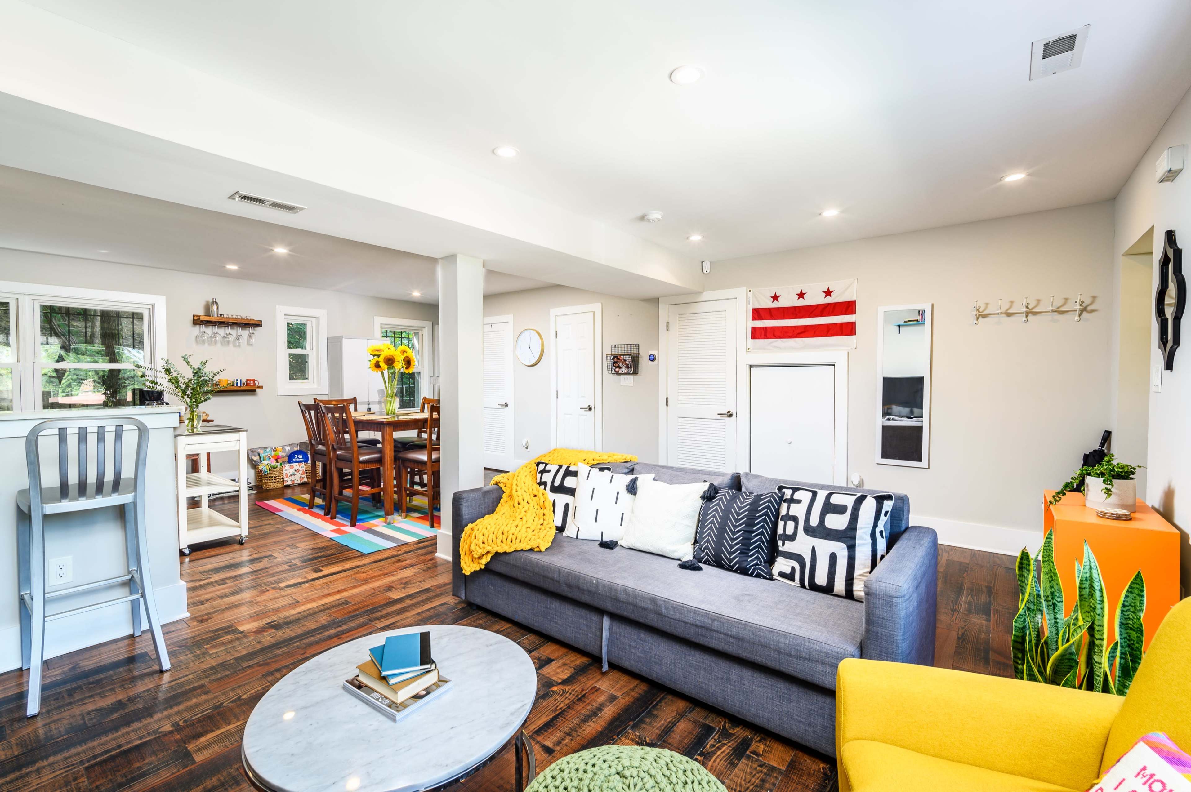 A bright and modern open-concept living area featuring a sofa, coffee table, and dining space with a table surrounded by chairs.