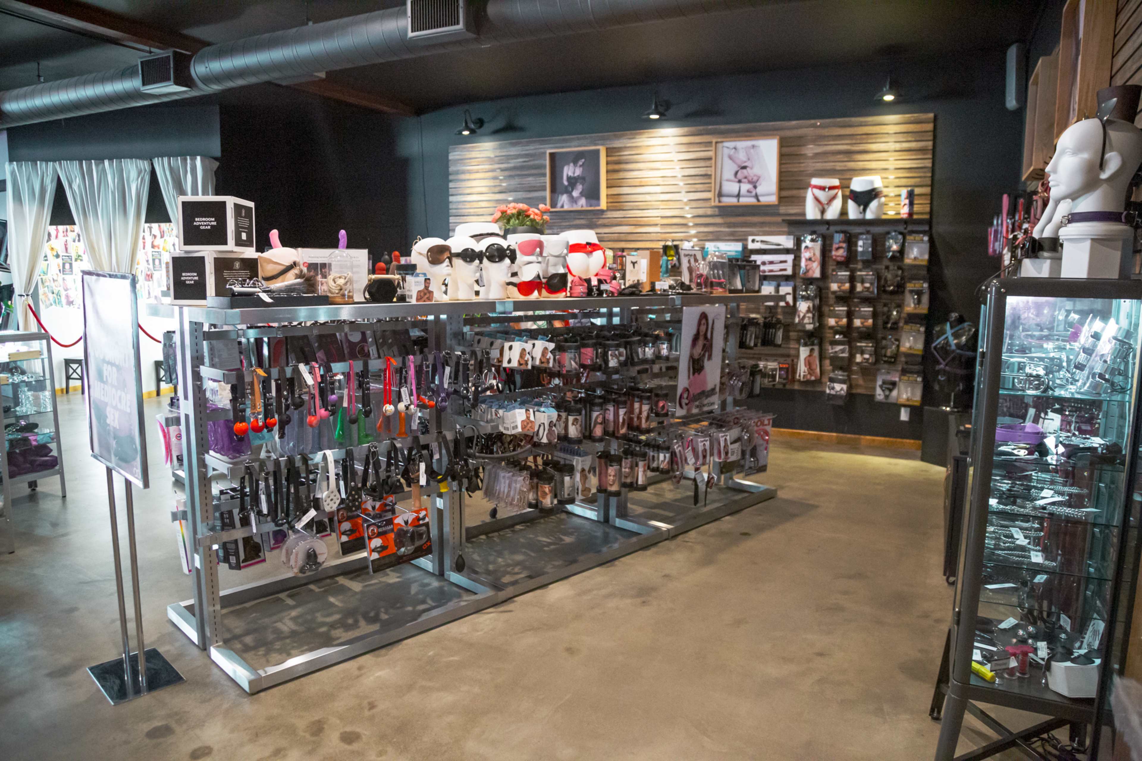 An adult novelty store with shelves displaying various products, including toys and accessories, arranged on metal racks and walls.