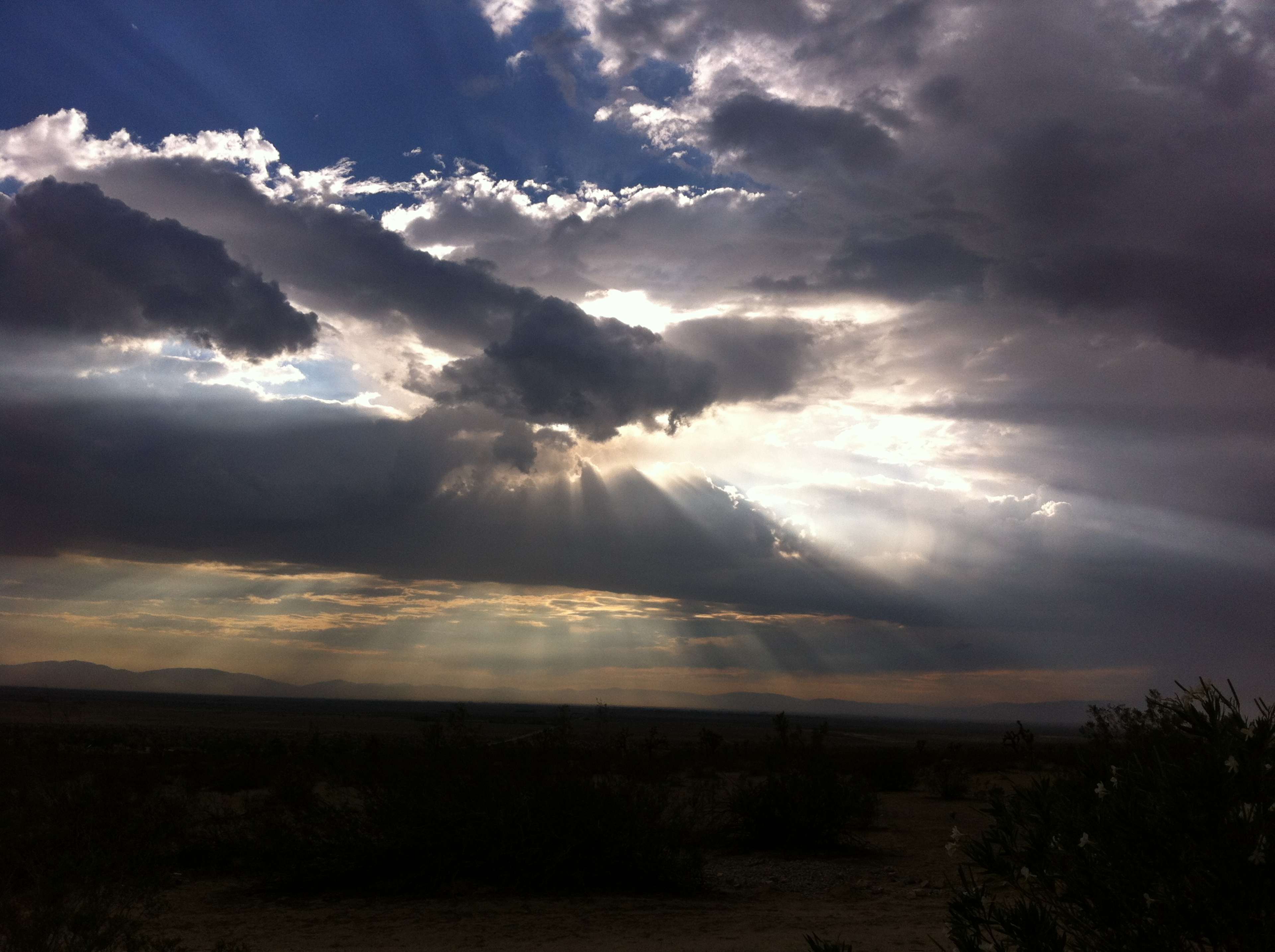 The image shows a dramatic sky with clouds and sunlight breaking through, illuminating the landscape below.