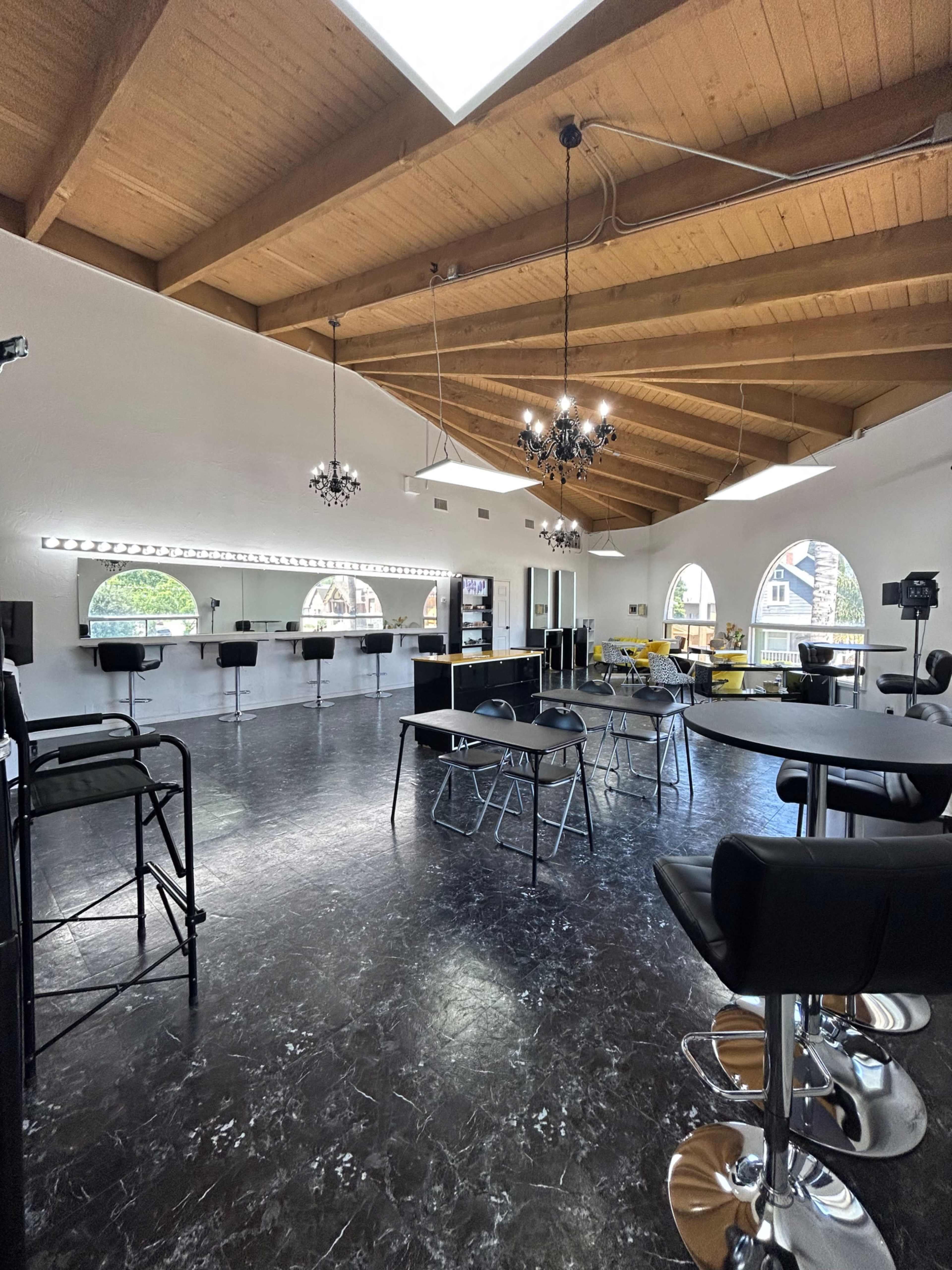 A spacious interior with high wooden ceilings, featuring various seating options and a large mirrored wall.