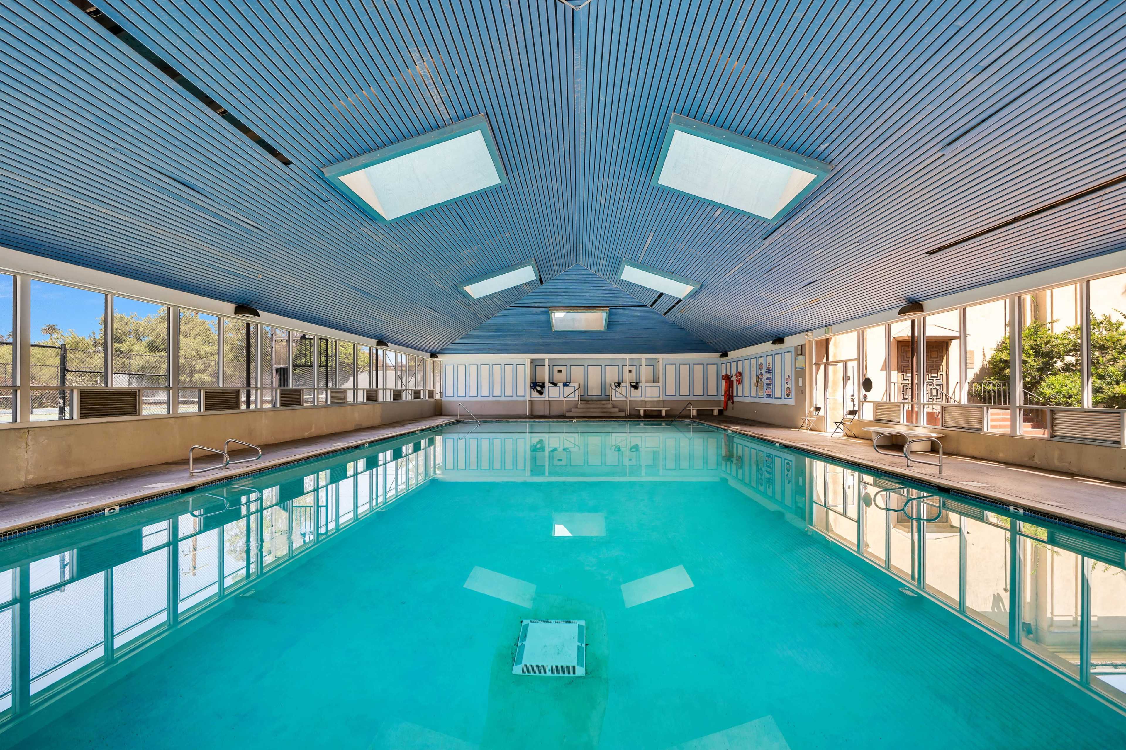 An indoor swimming pool with clear water and large windows that allow natural light to enter the space.