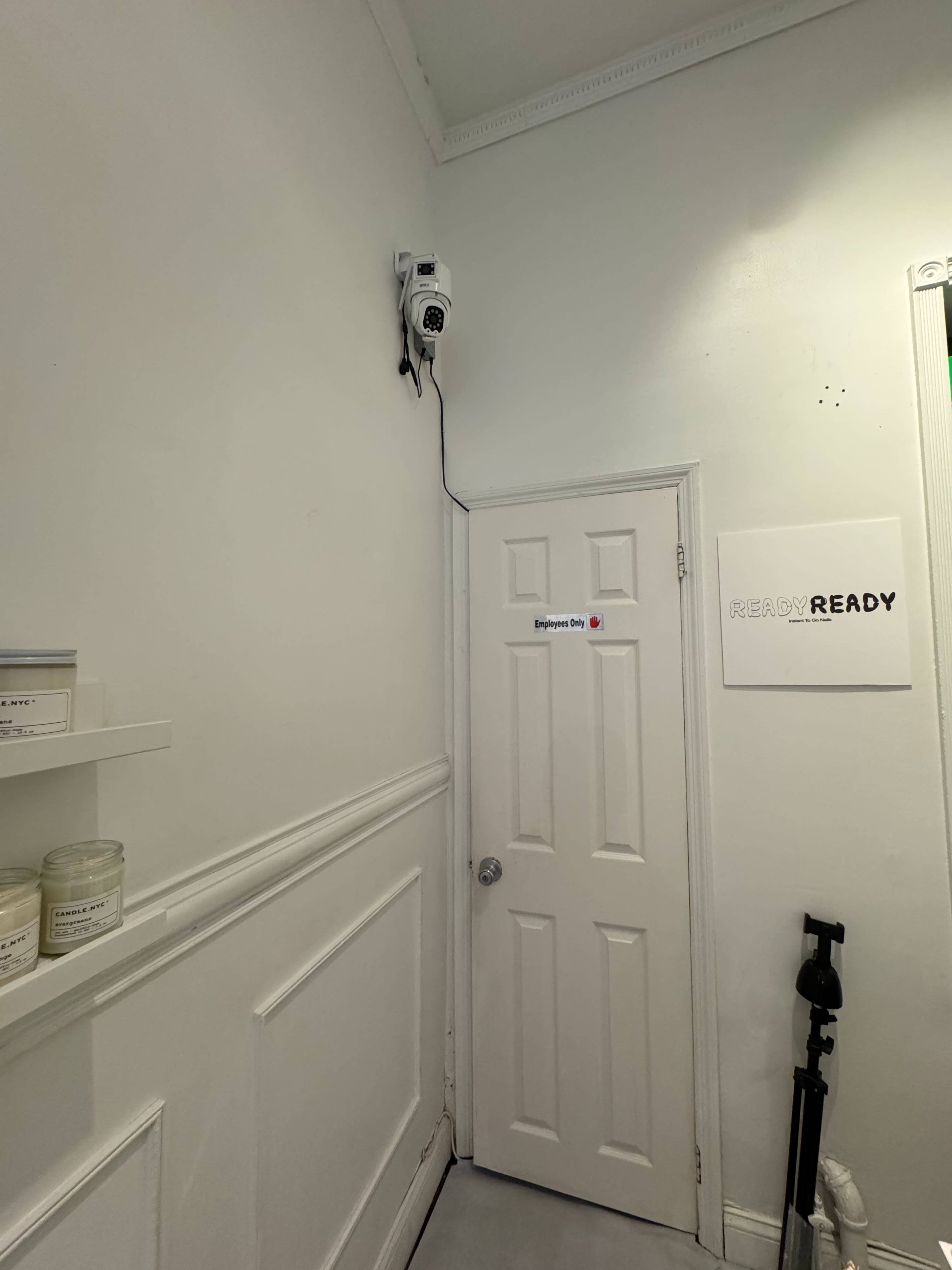 The image shows a corner of a room with a door, a wall-mounted device, and a sign that reads "READY."