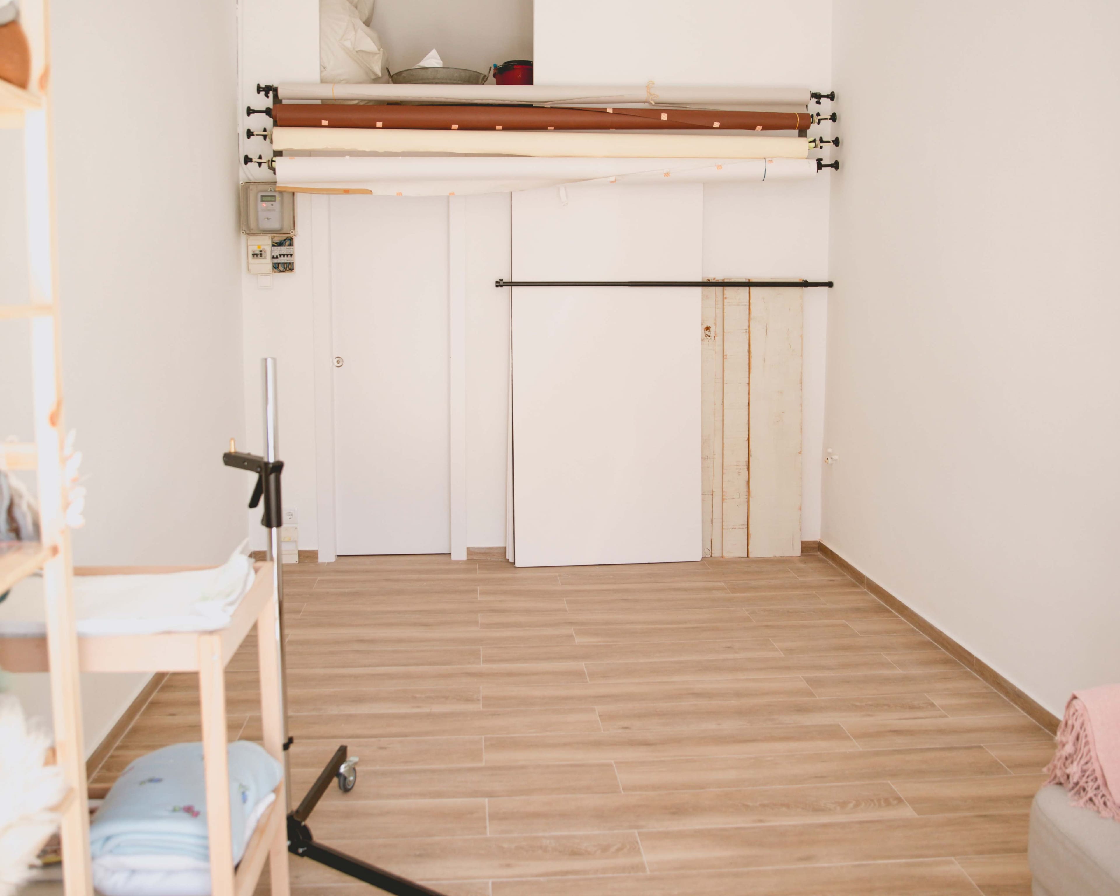An empty room with light-colored wooden flooring, white walls, and a lofted sleeping area above.