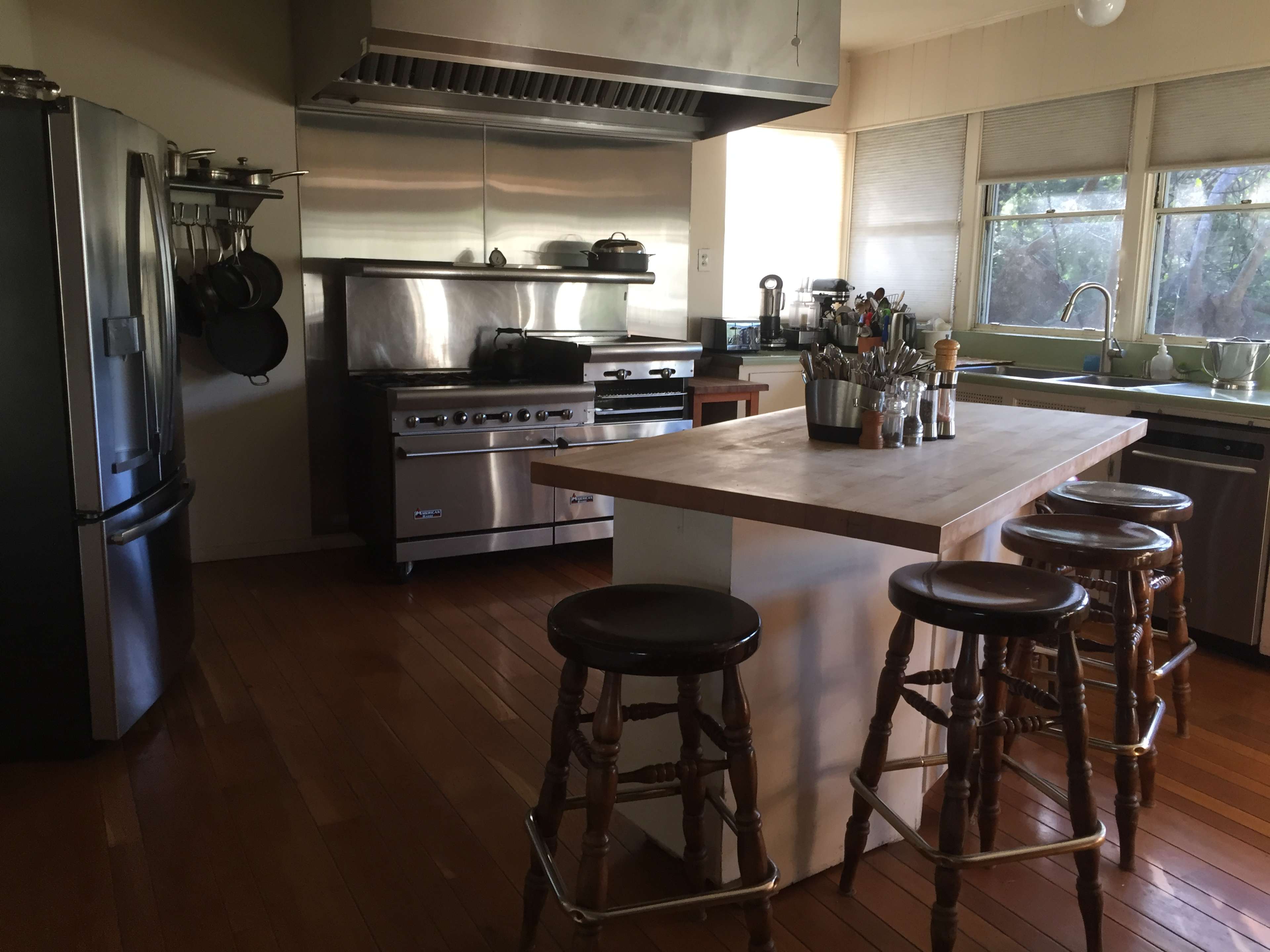 The kitchen features stainless steel appliances, a large island with bar stools, and a window allowing natural light.