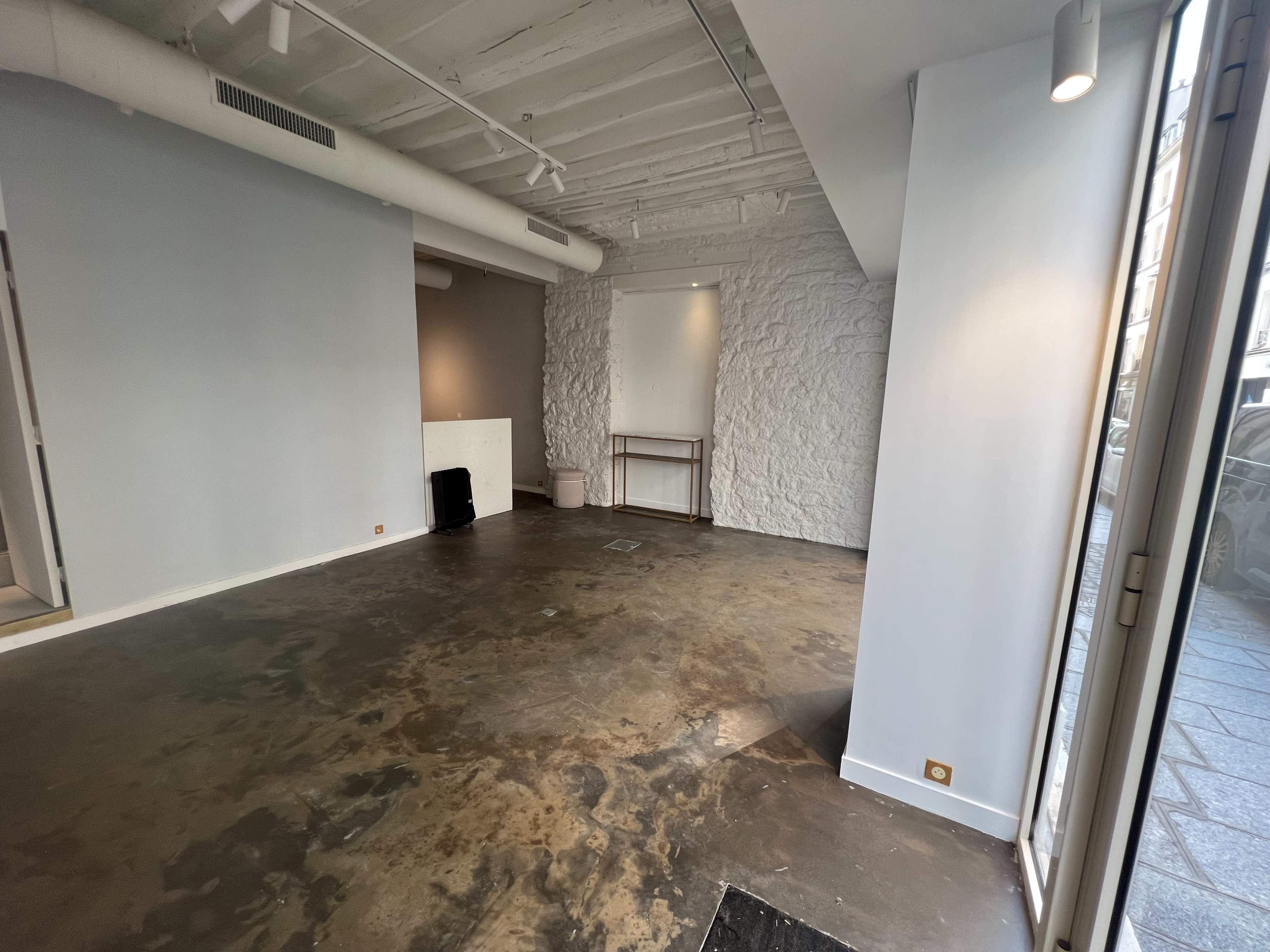 The image shows an empty commercial space with a concrete floor and light gray walls.