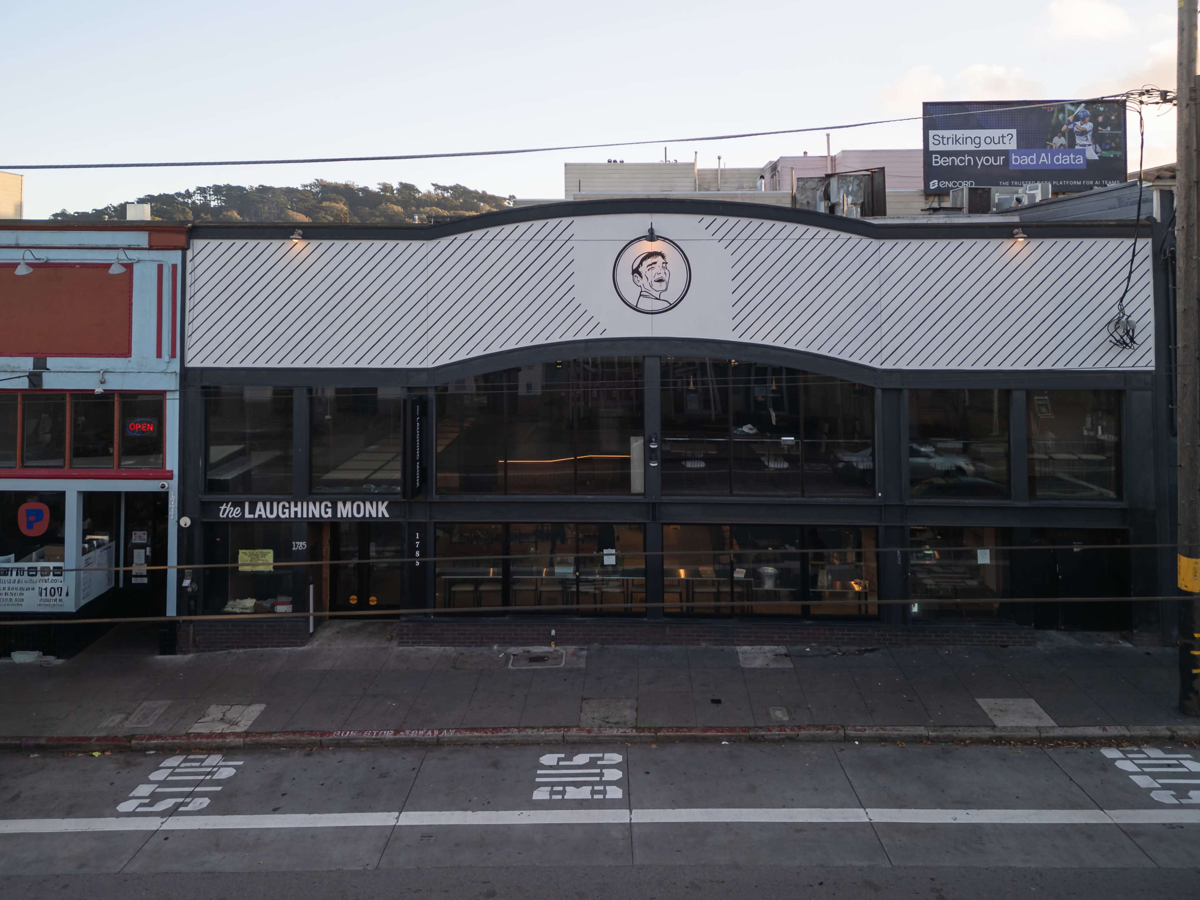 The image shows a facade of a building with the name "the LAUGHING MONK" prominently displayed above large glass windows.